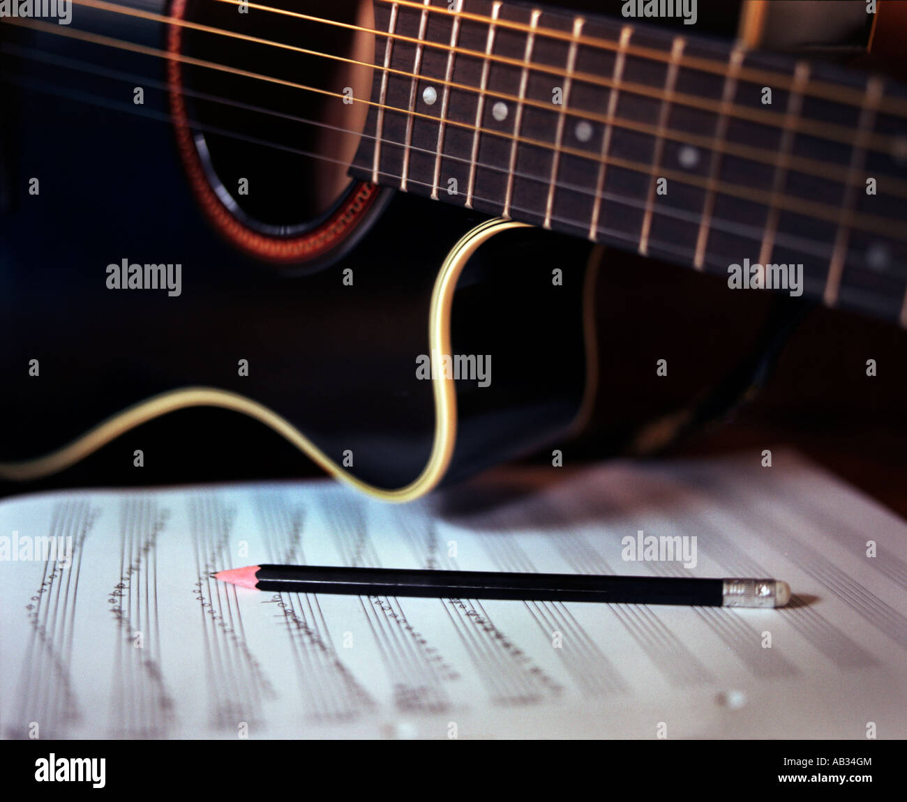 Una chitarra con una penna e un notebook Foto Stock