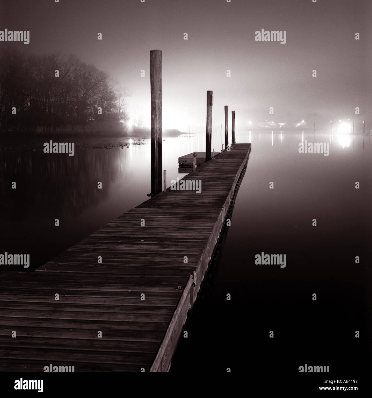 Dock che si estende fuori nella notte di nebbia nero e bianco paesaggio. Foto Stock