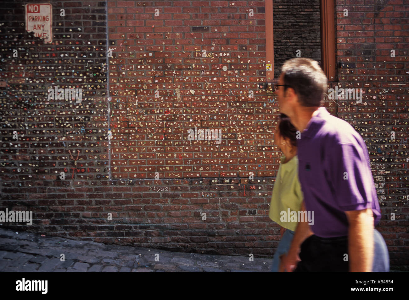 L uomo e la donna a camminare lungo la gomma da masticare parete teatro del mercato il Mercato di Pike Place Seattle Washington Foto Stock