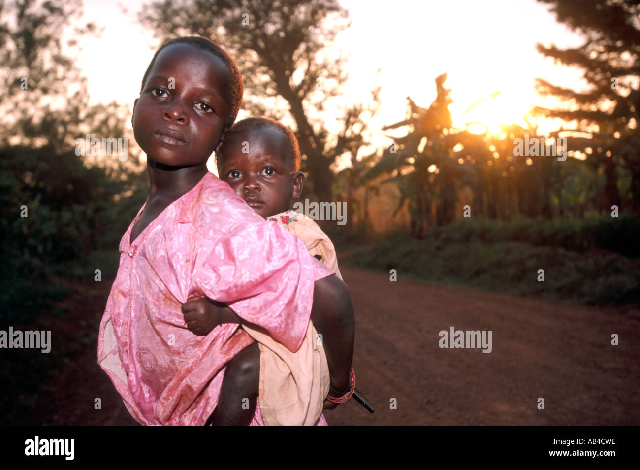 Triste guardando i giovani adolescenti ragazza locale che porta un bambino sulla schiena. Foto Stock