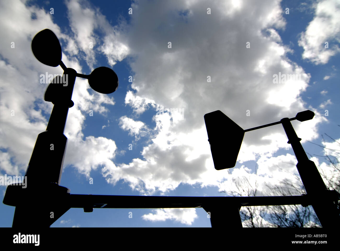 Un anemometro e banderuola stagliano contro un nuvoloso cielo blu. Foto Stock