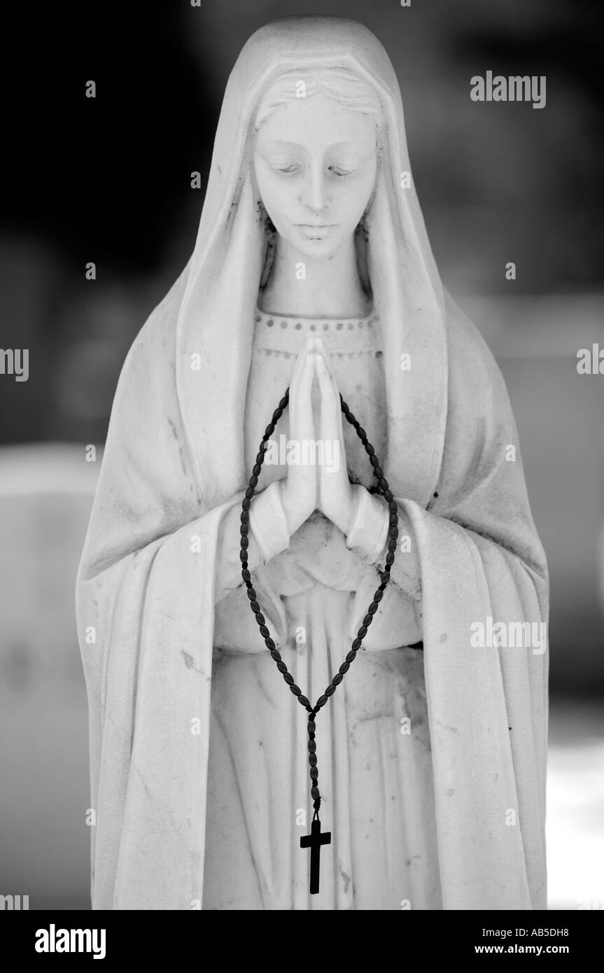 Statua raffigurante Maria tenendo un crocifisso in un cimitero Foto Stock