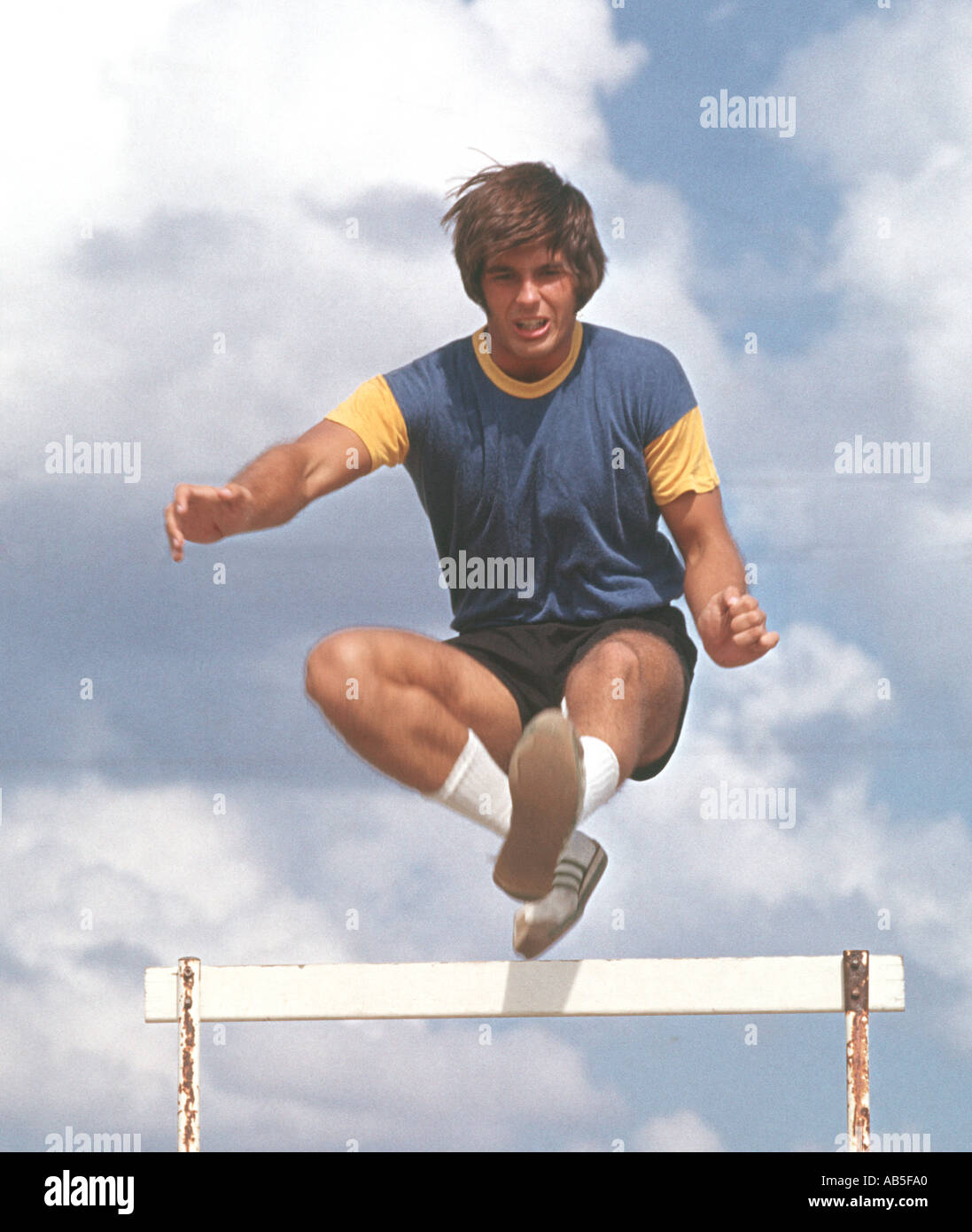 Atleta maschio saltando ostacoli a scuola via soddisfare Foto Stock