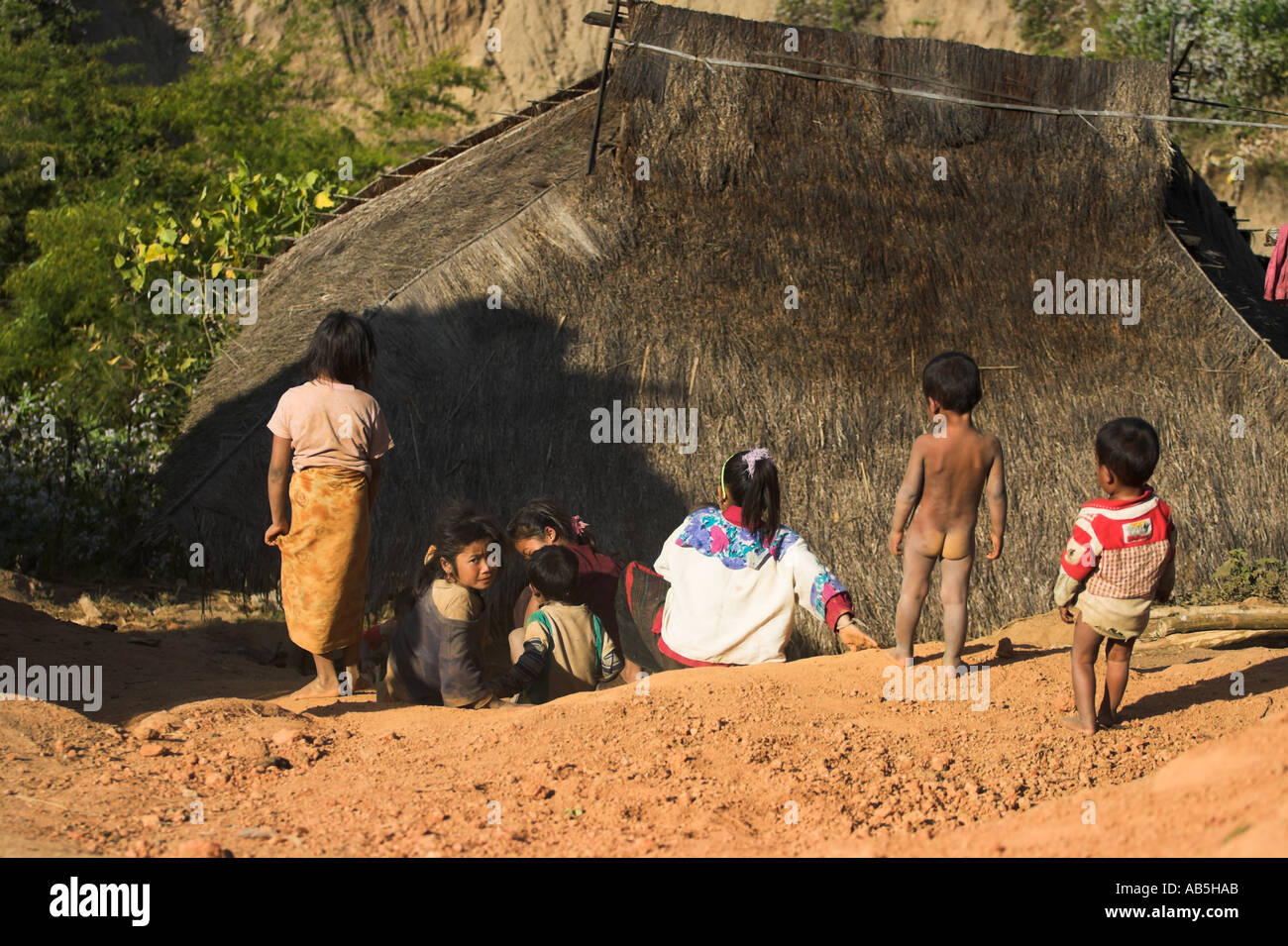 Myanmar stato Shan Kengtung Ann Village Ann i bambini lo scorrimento verso il basso della pendenza di fango al di fuori di casa di paglia Foto Stock