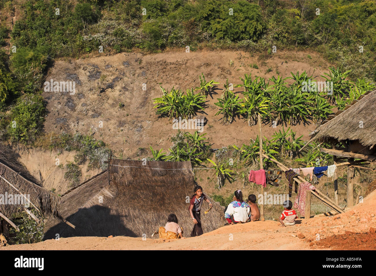 Myanmar stato Shan Kengtung Kyaing Tong Ann Village Ann i bambini lo scorrimento verso il basso della pendenza di fango al di fuori di casa di paglia Foto Stock