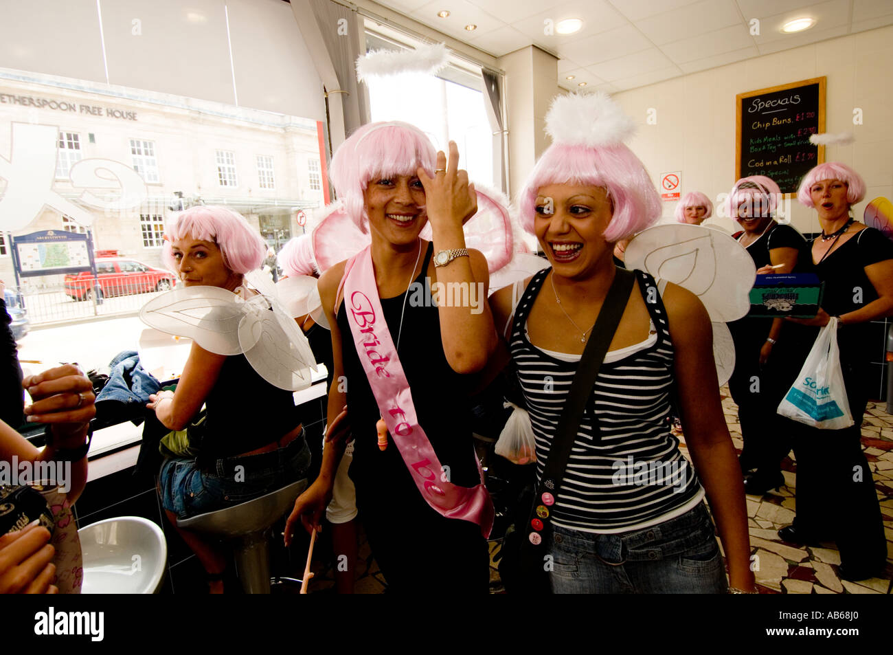 Ragazze in chip shop in Aberystwyth vestito come dai capelli rosa degli angeli con ali sulla loro notte di gallina - Celebrazioni - Sposa per essere Foto Stock