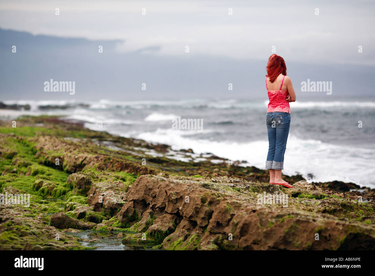 Una giovane donna che guarda all'oceano di Maui, Hawaii Foto Stock