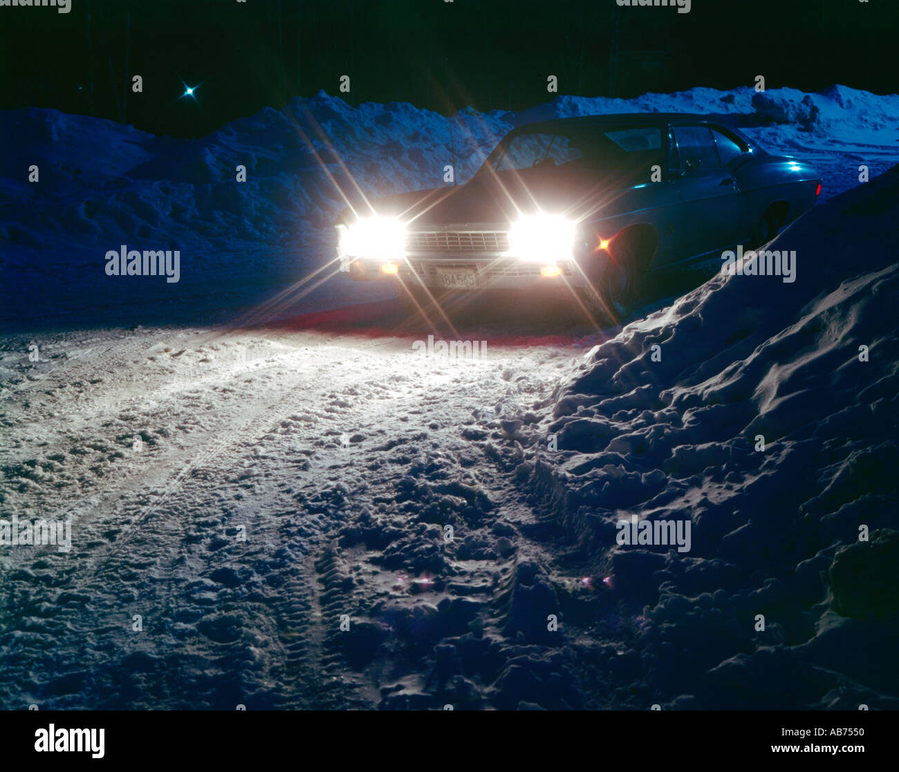 Auto guidando lentamente durante la notte su strade coperte di neve road Foto Stock