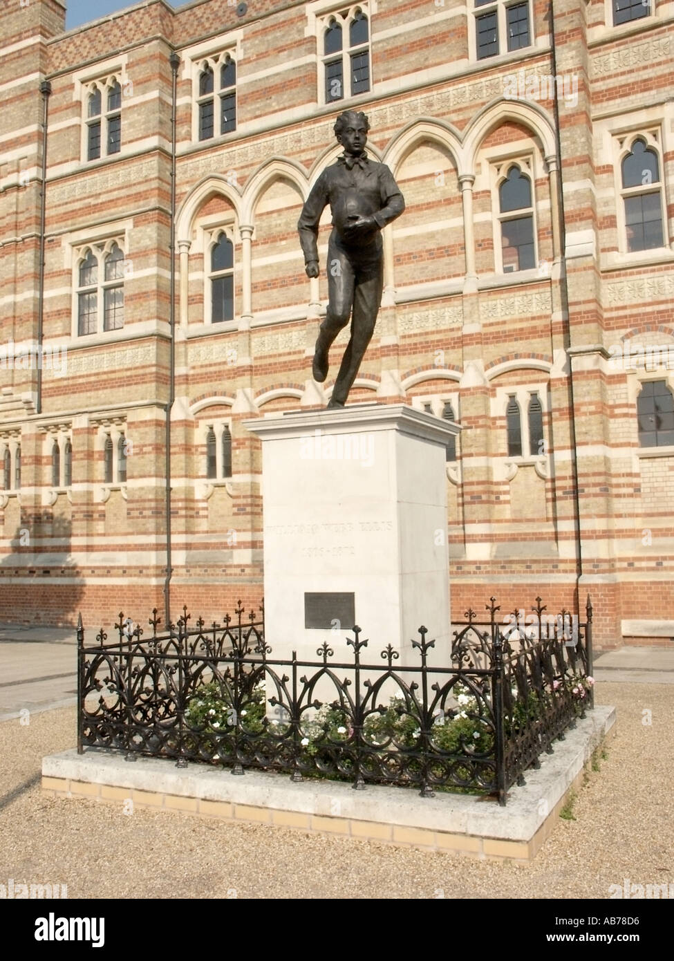 Statua di William Webb Ellis commemorare holding e in esecuzione con un calcio crea così lo sport del rugby al di là della scuola Foto Stock