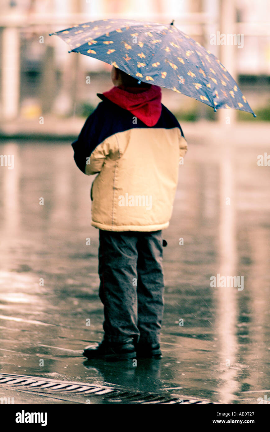Bambino sotto un ombrello sotto la pioggia Foto Stock