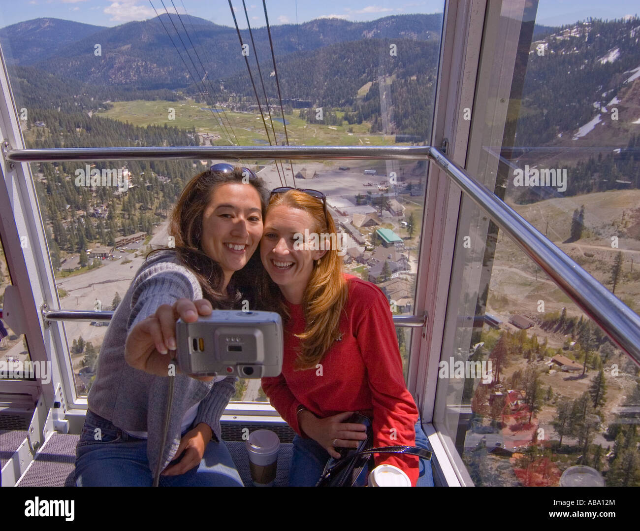 Due donne facendo loro foto sul viaggio in cabinovia da Squaw Valley Village a High Camp Squaw Valley in California Foto Stock