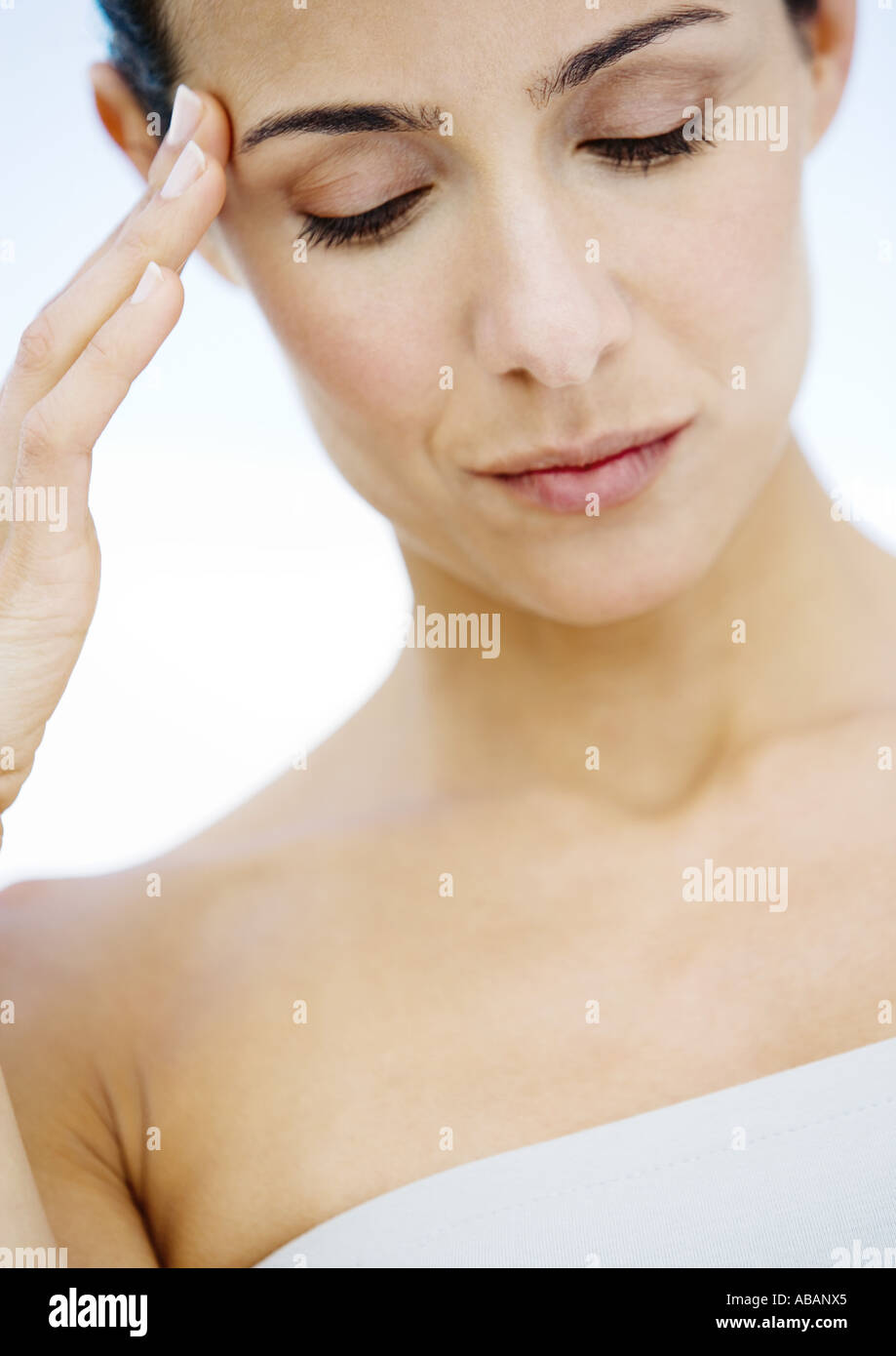 Donna con le dita sul lato della testa e gli occhi abbassati Foto Stock