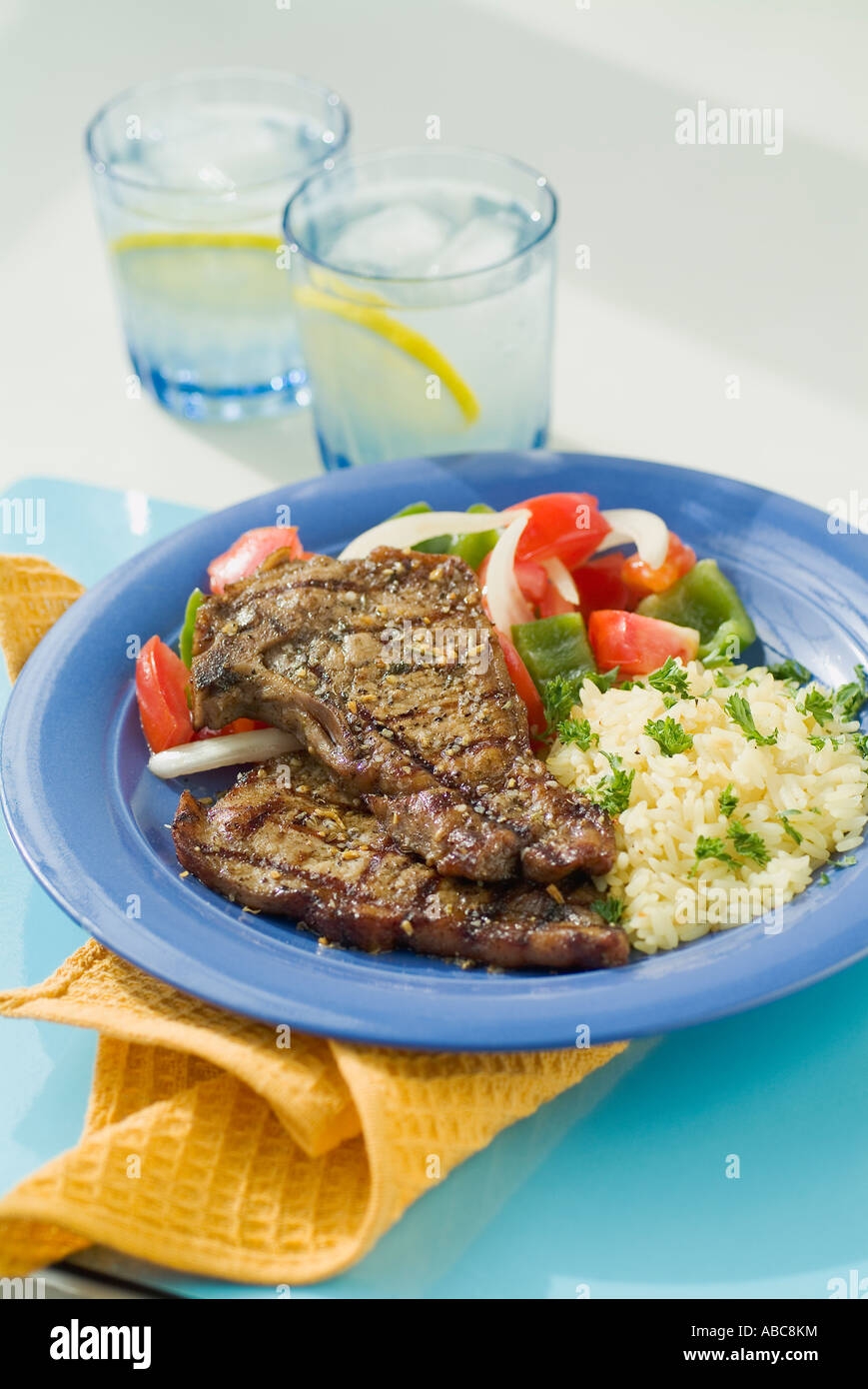 Barbeque costolette di maiale con il riso e le verdure su una piastra blu con limonata fresca. Foto Stock