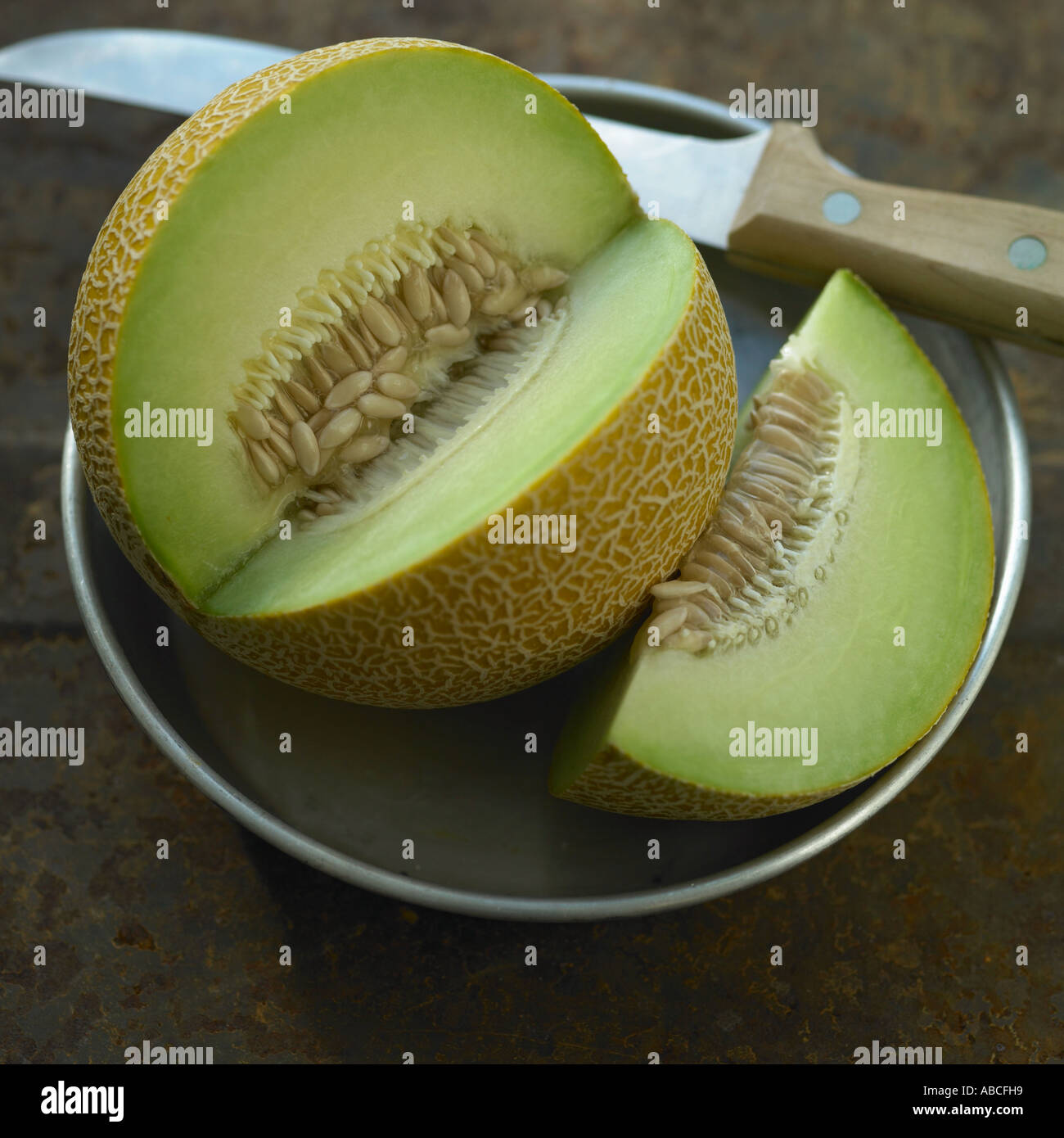 Melone Galia con coltello sulla piastra di metallo Foto Stock