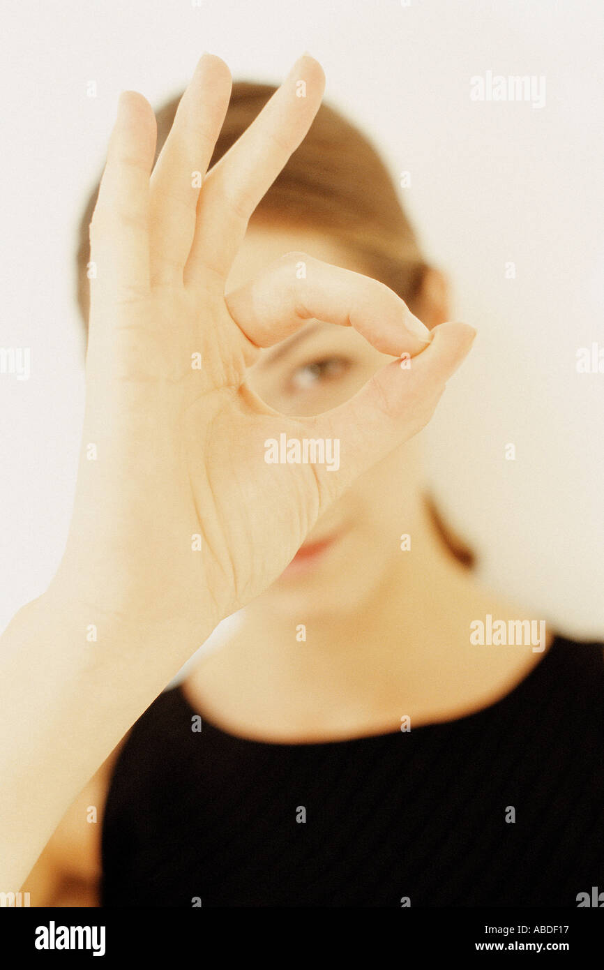 Una giovane donna incorniciare una parte della sua faccia con le mani mostrando il suo occhio sinistro Foto Stock