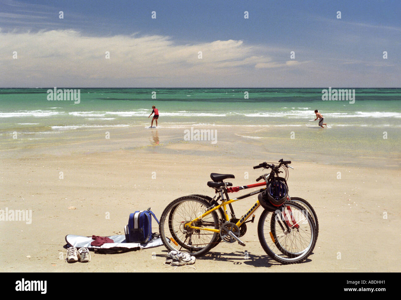 Ragazzi giocando sulla spiaggia sabbiosa bikes abbigliamento e zaini in primo piano Foto Stock