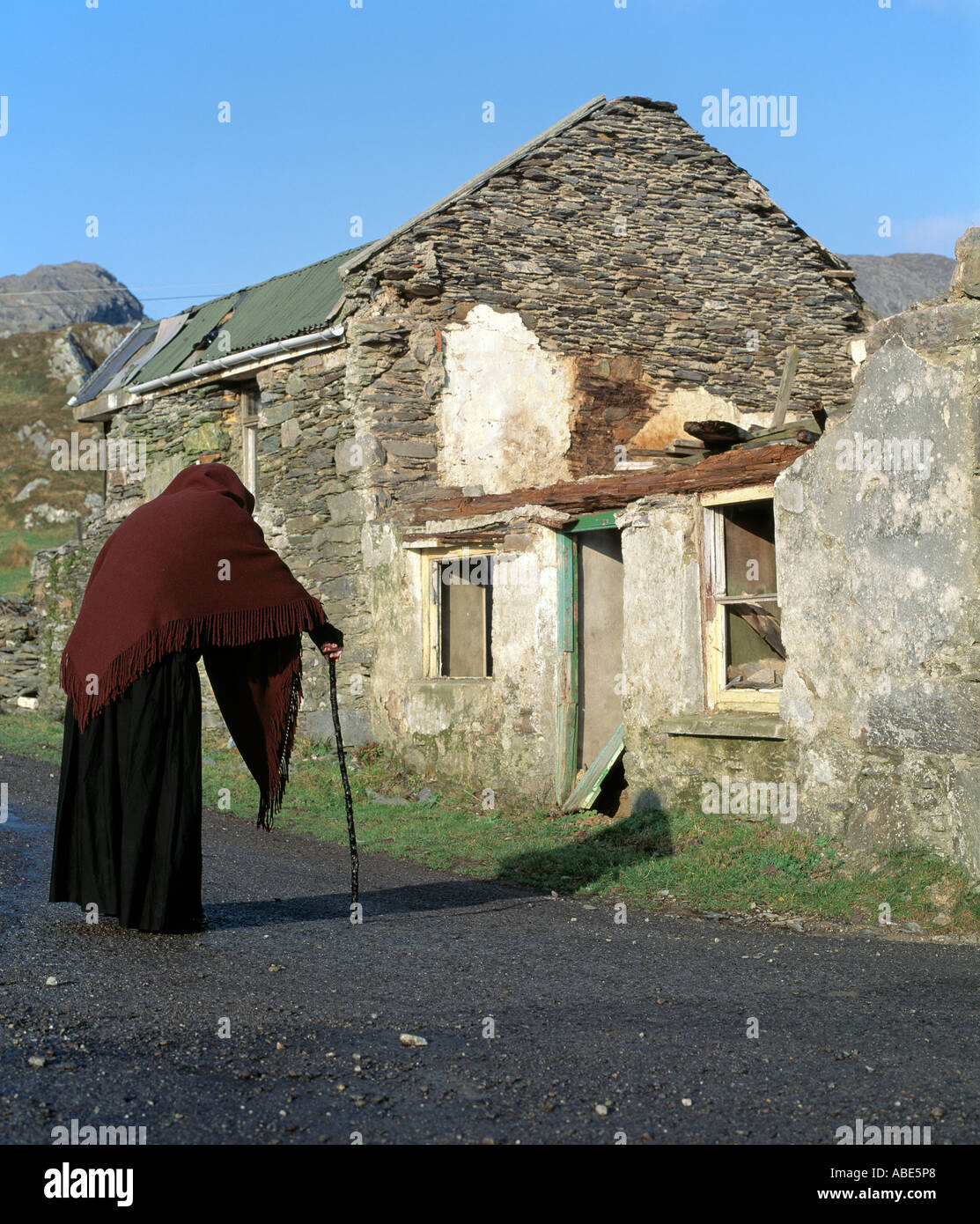 Il vecchio donna che indossa uno scialle in piedi di fronte a una casa in  rovina Foto stock - Alamy