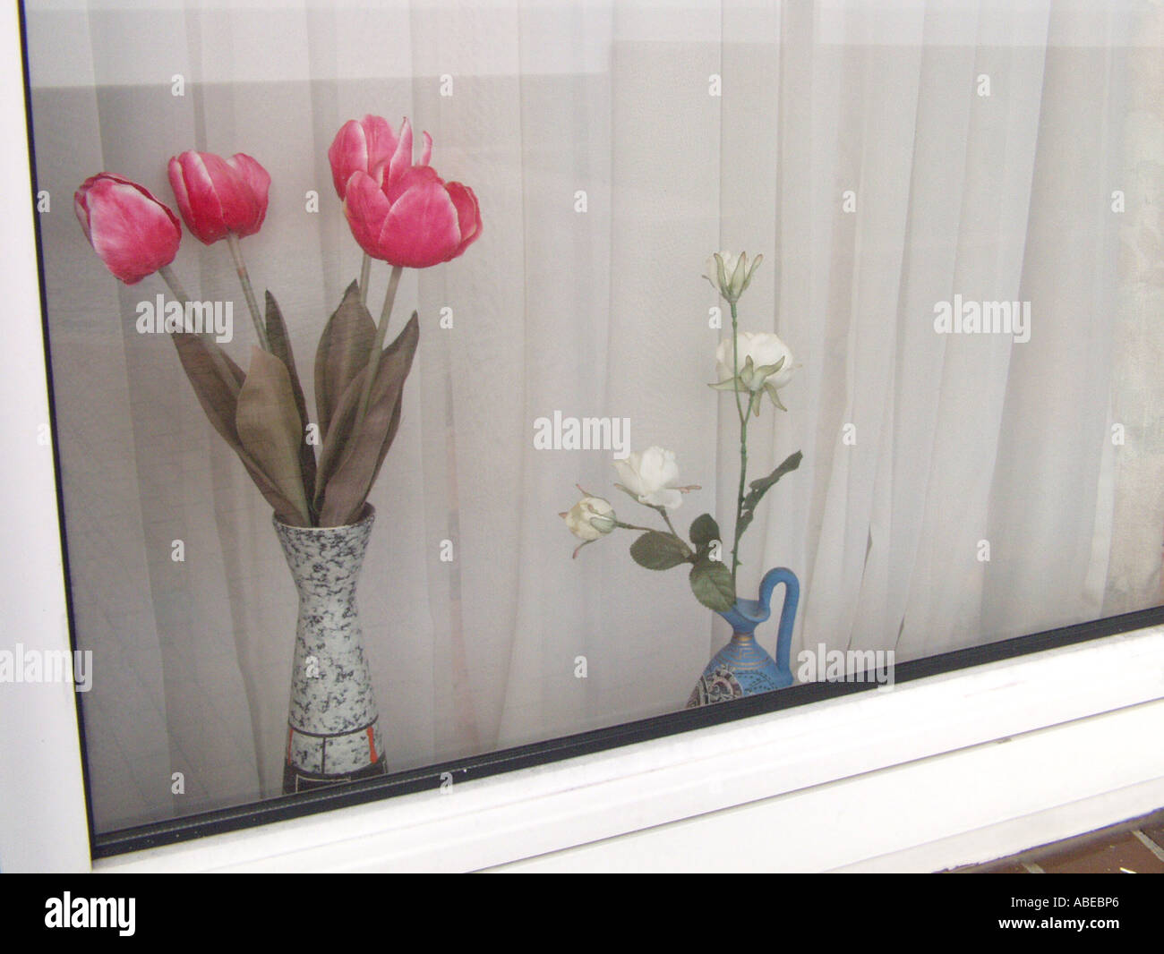 I fiori di plastica in una finestra Foto Stock
