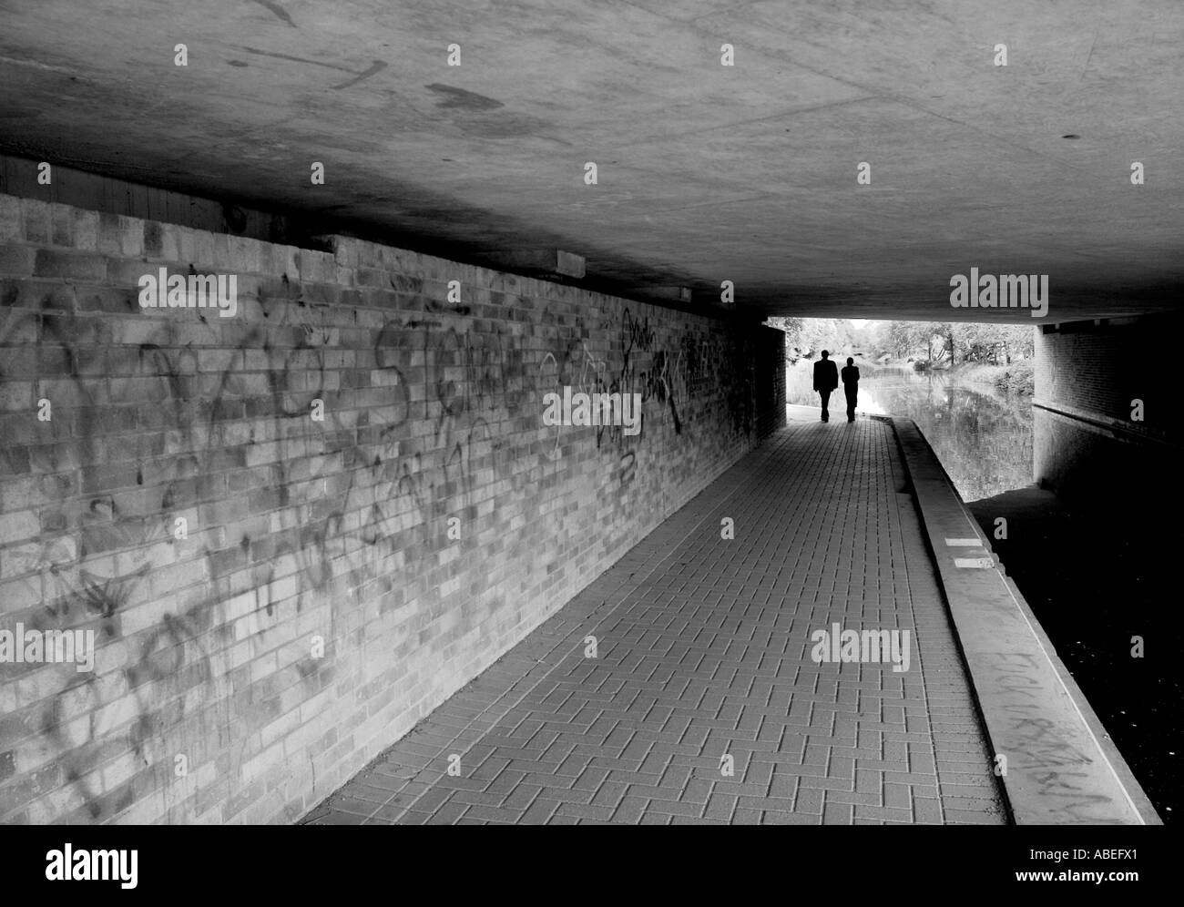 Due estranei a piedi sotto un ponte sul canale sul Basingstoke Canal Woking Foto Stock