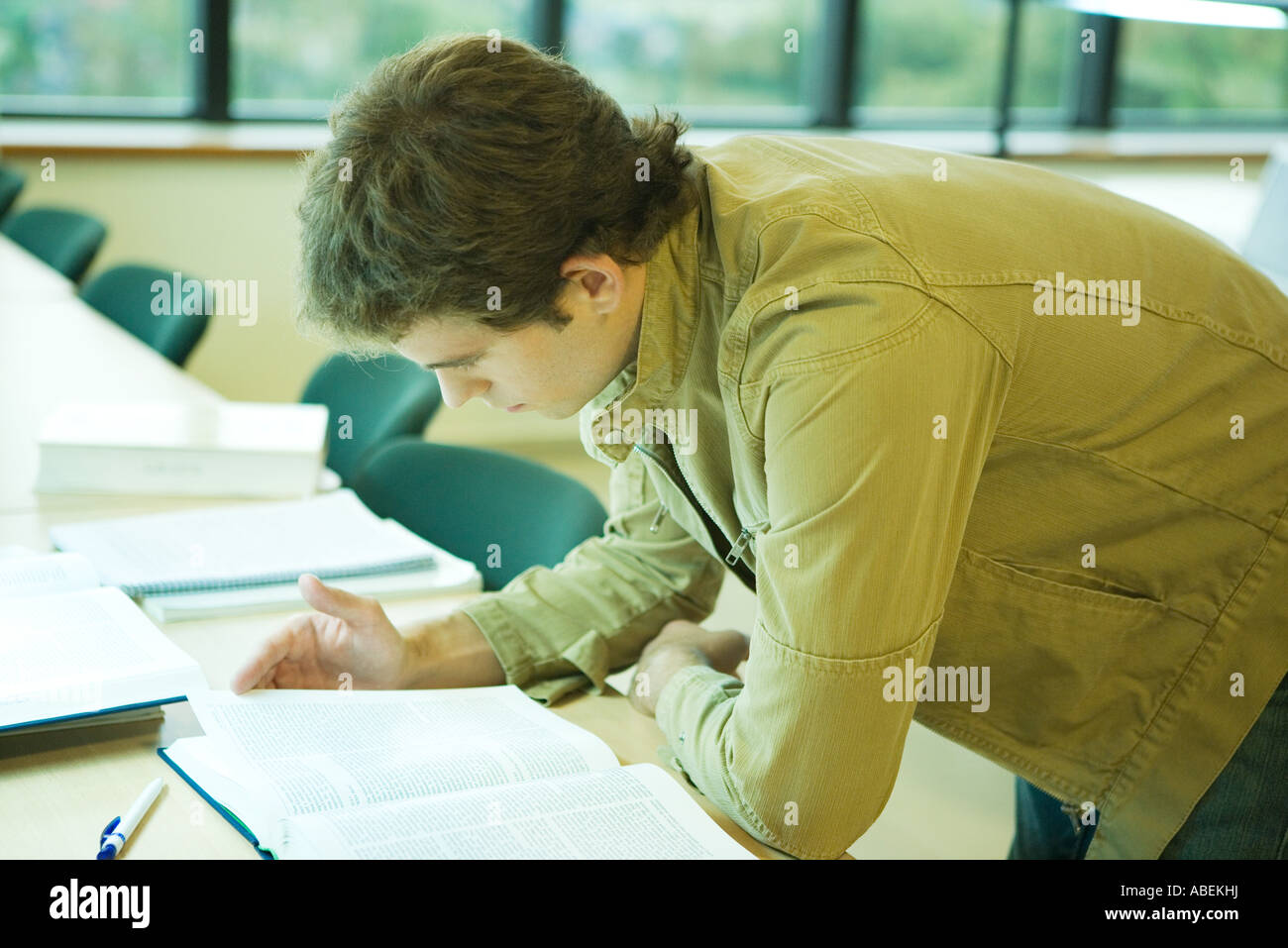 Collegio maschile studente sporgersi in avanti sul tavolo, studiare Foto Stock