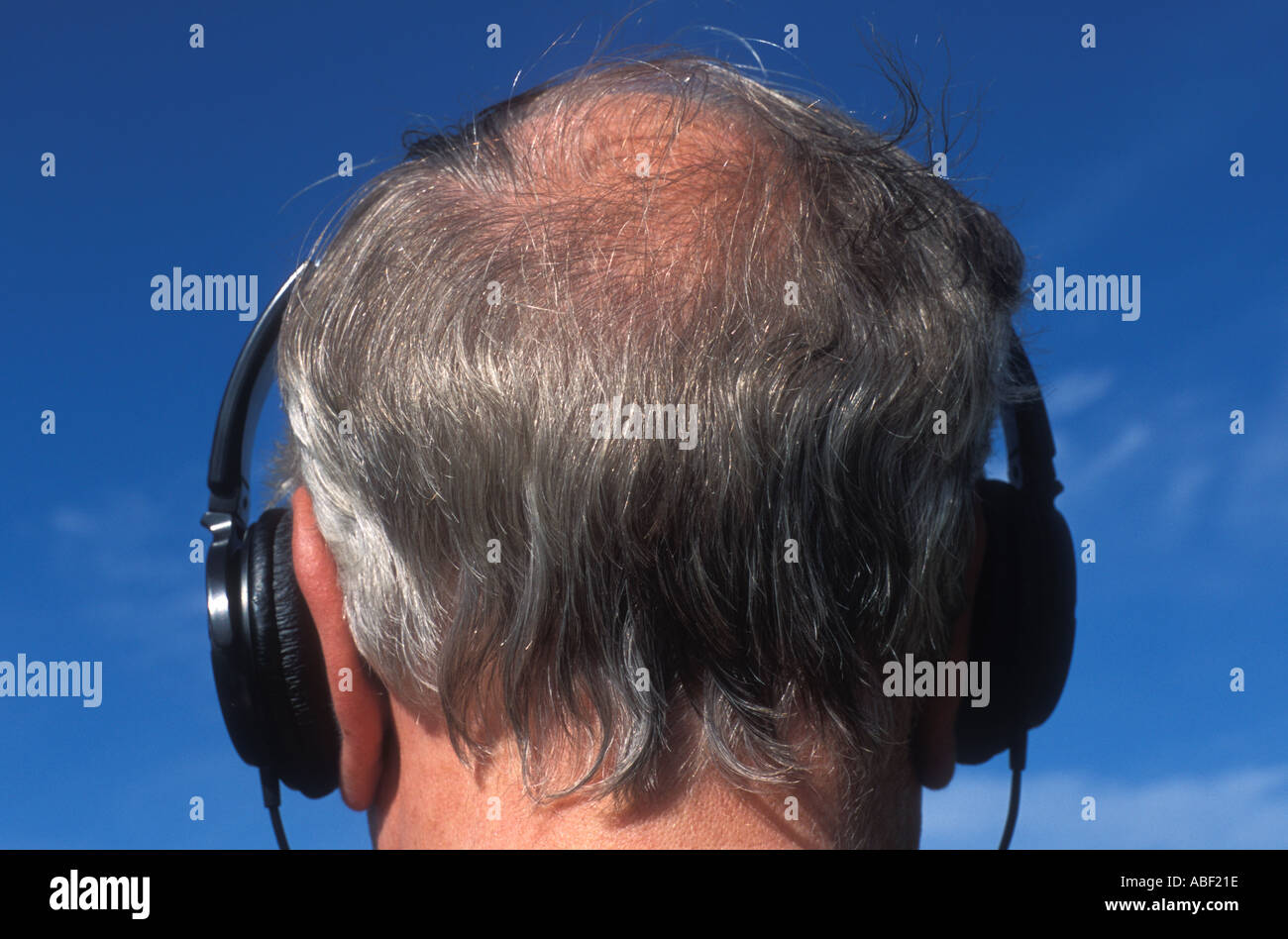 Uomo con cuffie su balding testa grigia Foto Stock