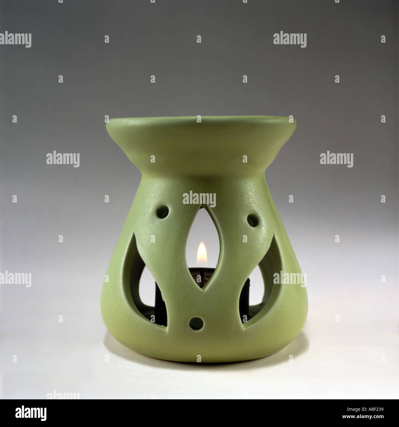 Bruciatore ad olio su uno sfondo grigio con un acceso "tè" luce di candela Foto Stock
