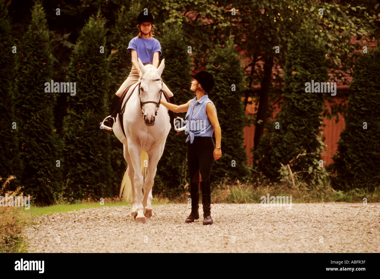 9 A 9 anno vecchia ragazza prende una lezione di equitazione su un purosangue da un trainer Foto Stock