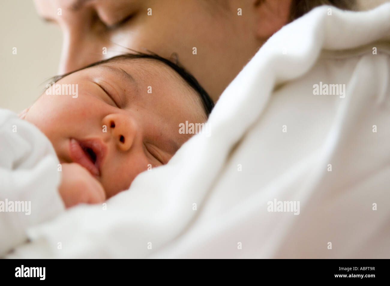 Baby girl dorme sulla sua mamma spalla. La mamma ha gli occhi chiusi come bene. Foto Stock