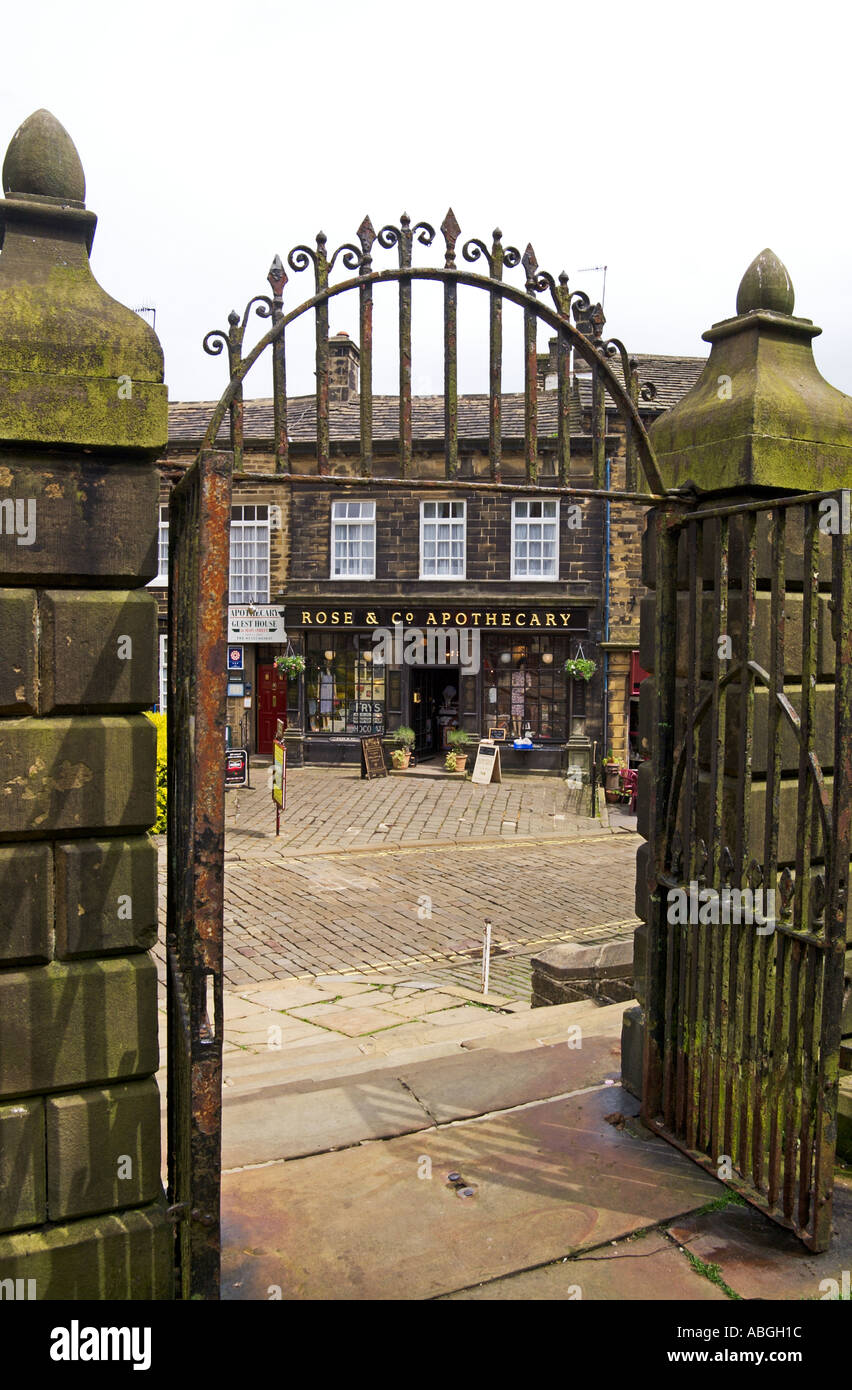 Strada di ciottoli e speziale shop attraverso le porte della chiesa a Haworth West Yorkshire Inghilterra Foto Stock