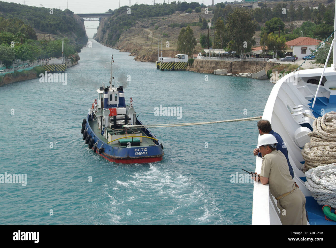 La nave di crociera in procinto di passare attraverso lo stretto canale di Corinto assistita dal rimorchiatore Foto Stock