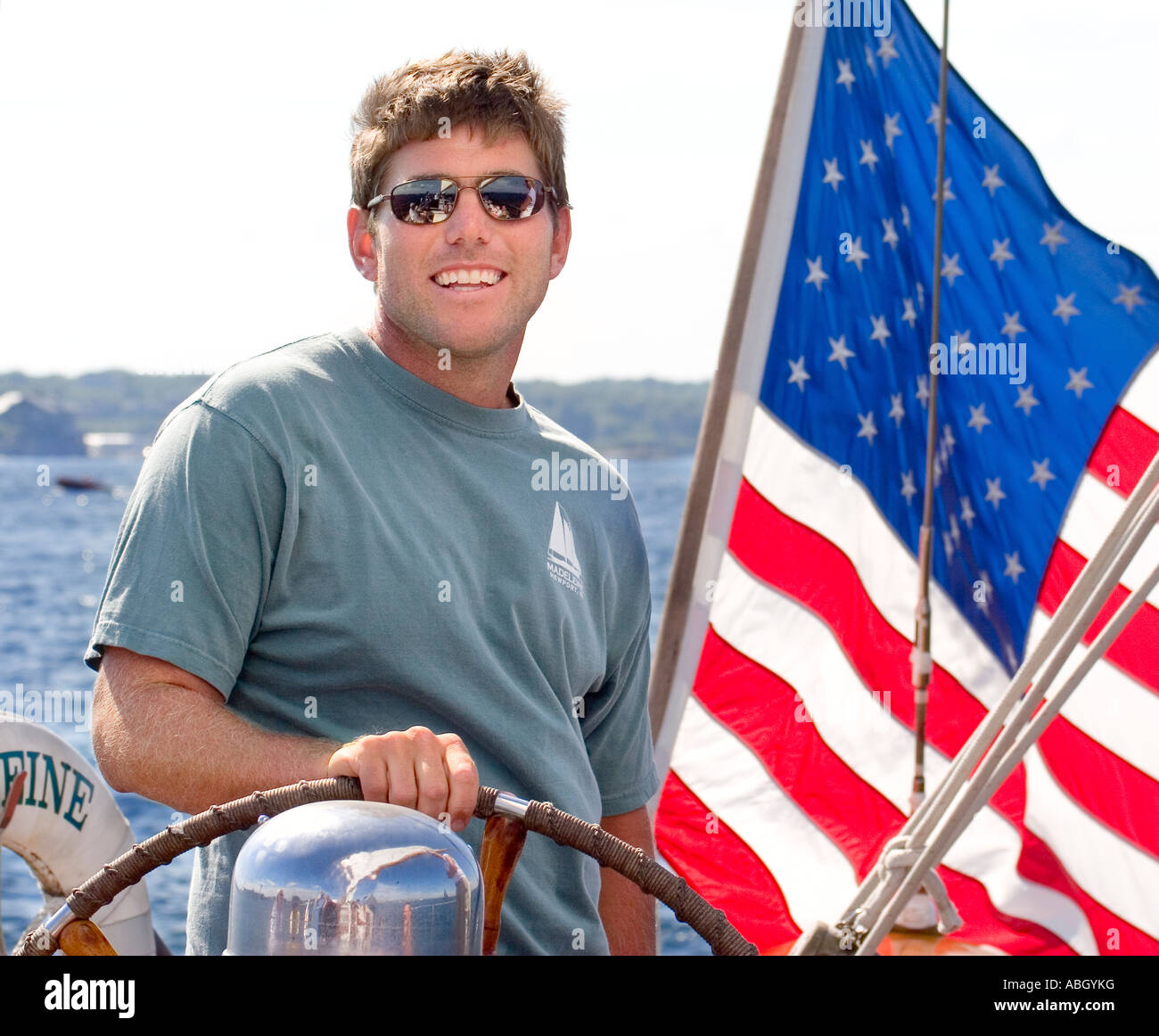 Il capitano di un sailbot in Rhode Island in piedi di fronte a una bandiera americana. Foto Stock