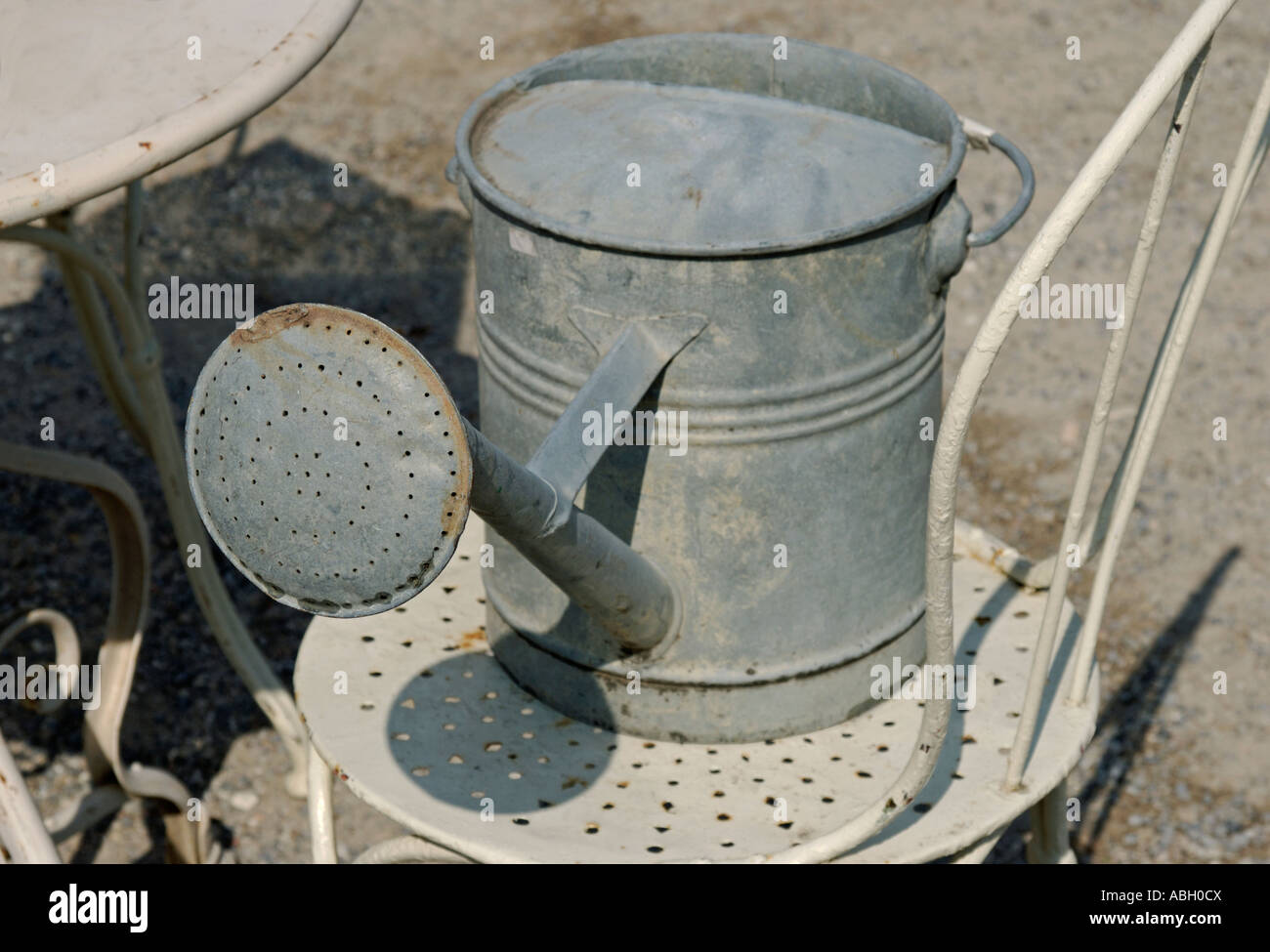 Irrigazione di zinco può su una sedia in metallo Foto Stock