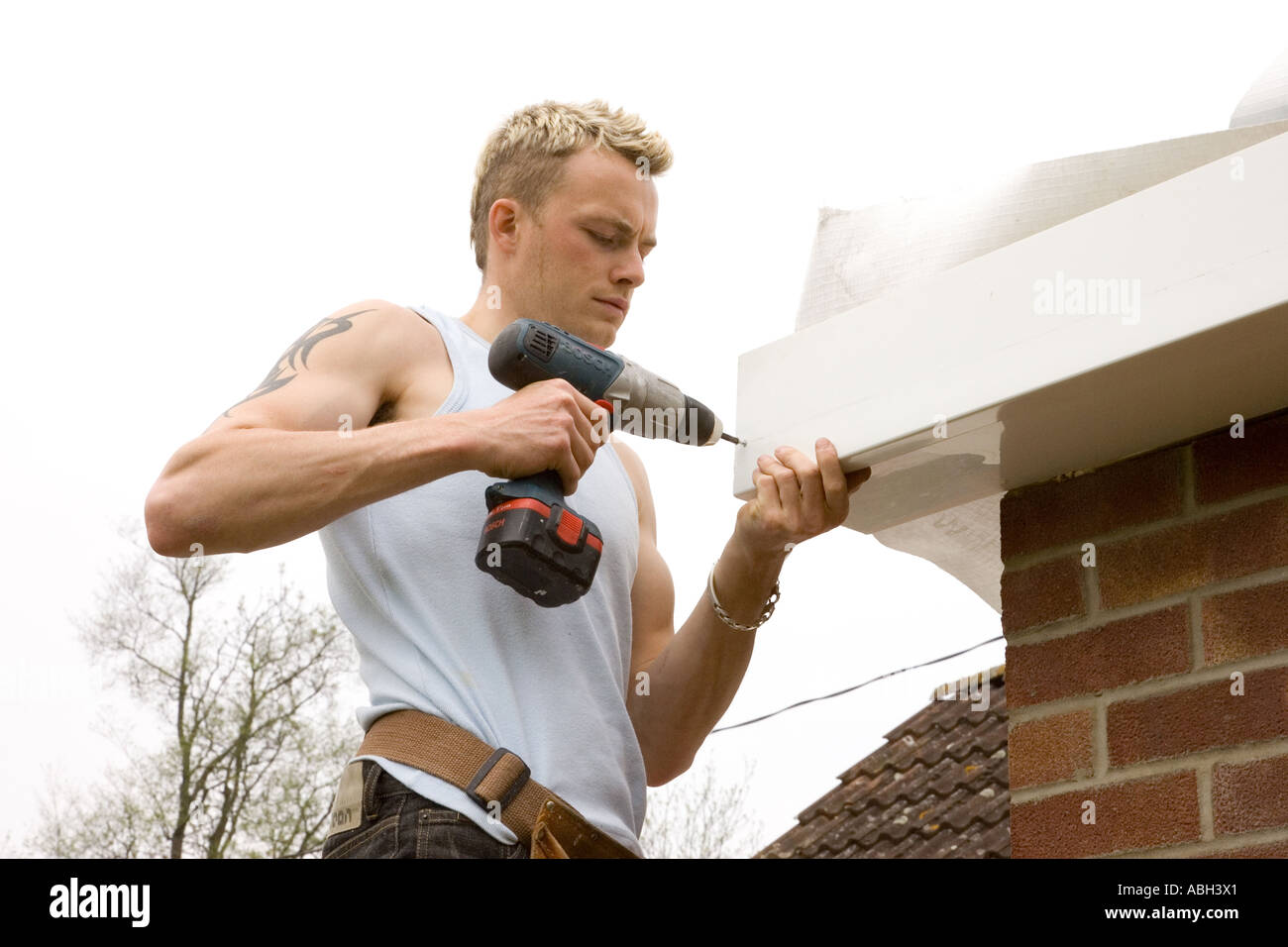 Un costruttore di installare un uPVC pannello Facia al di sotto di un tetto di una casa. Foto Stock