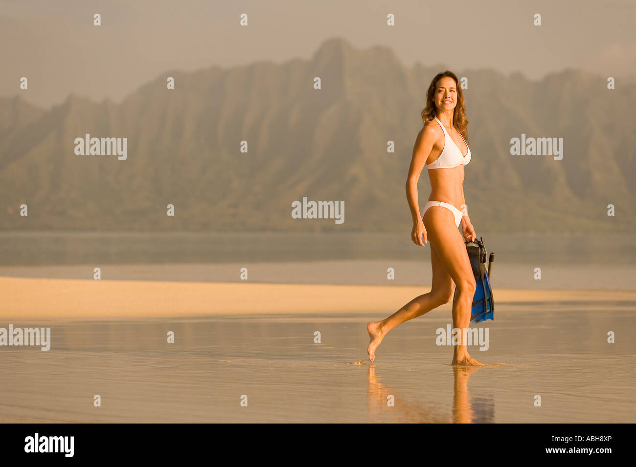 A piedi femmina sabbia esposto bar nella Baia di Kaneohe montagne Koolau a Kualoa e Mokolii isola come sfondo Foto Stock