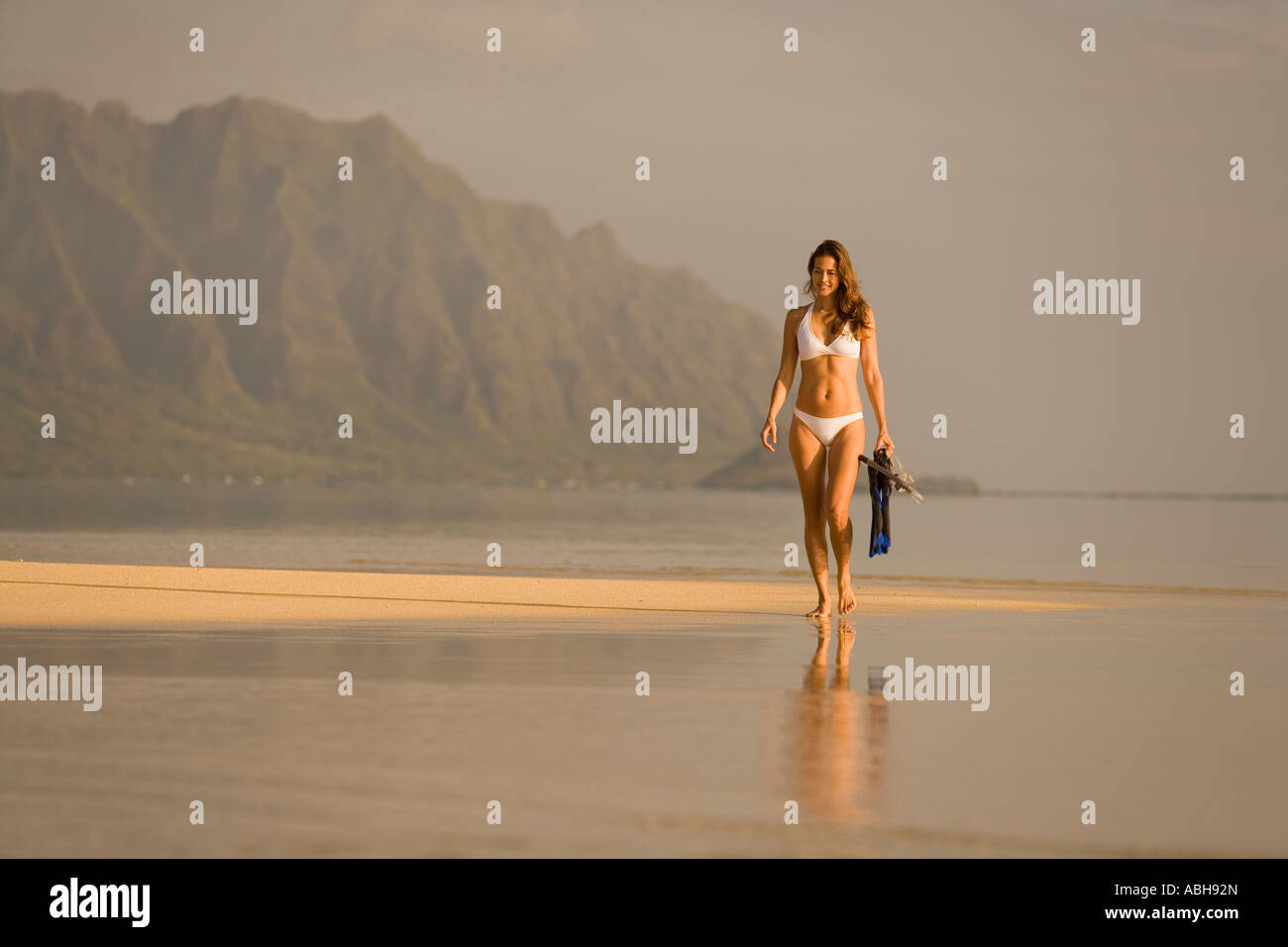 A piedi femmina sabbia esposto bar nella Baia di Kaneohe montagne Koolau a Kualoa come sfondo Foto Stock