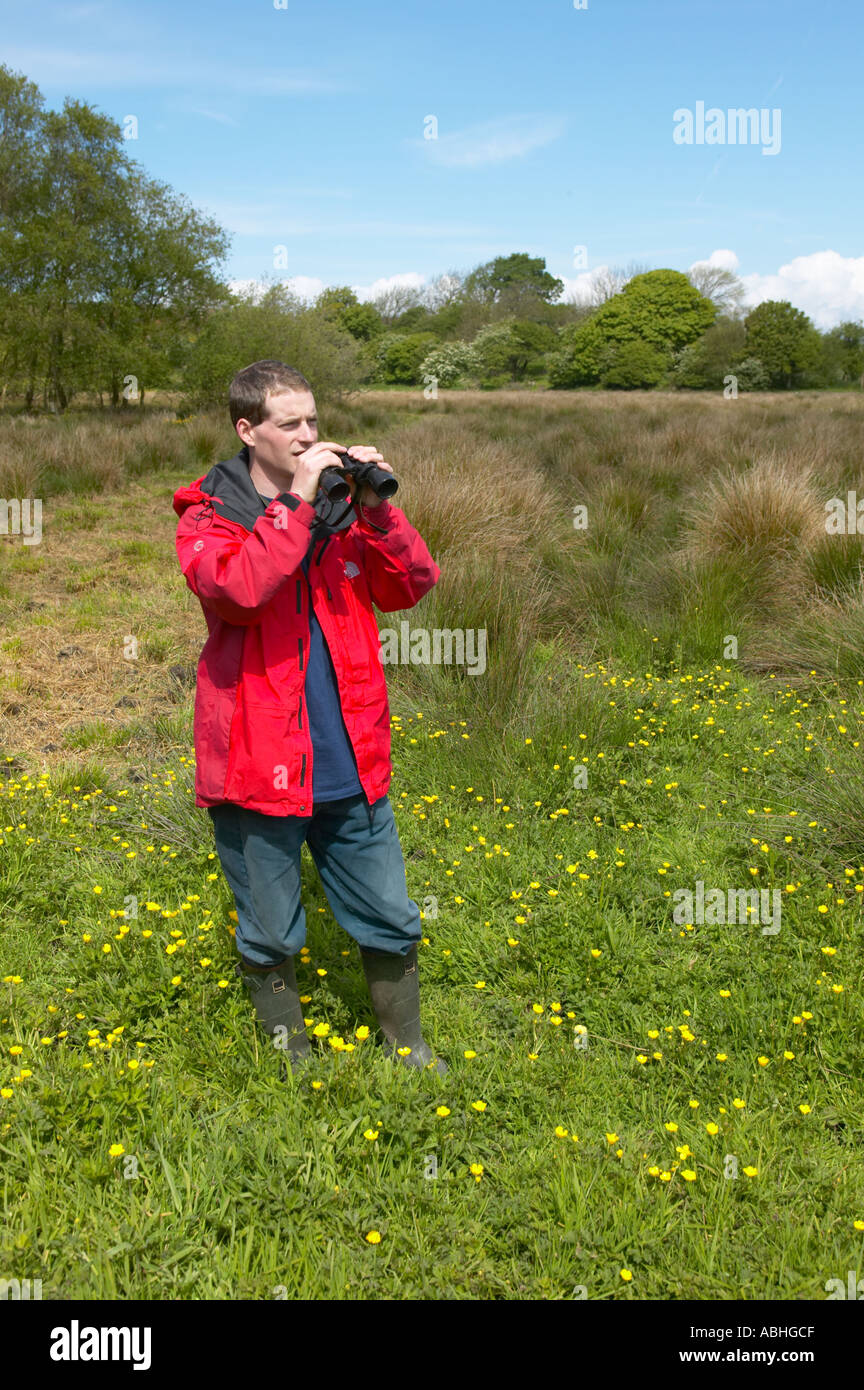 L'uomo birding guardando ad Heysham Moss riserva naturale con la giacca rossa Foto Stock