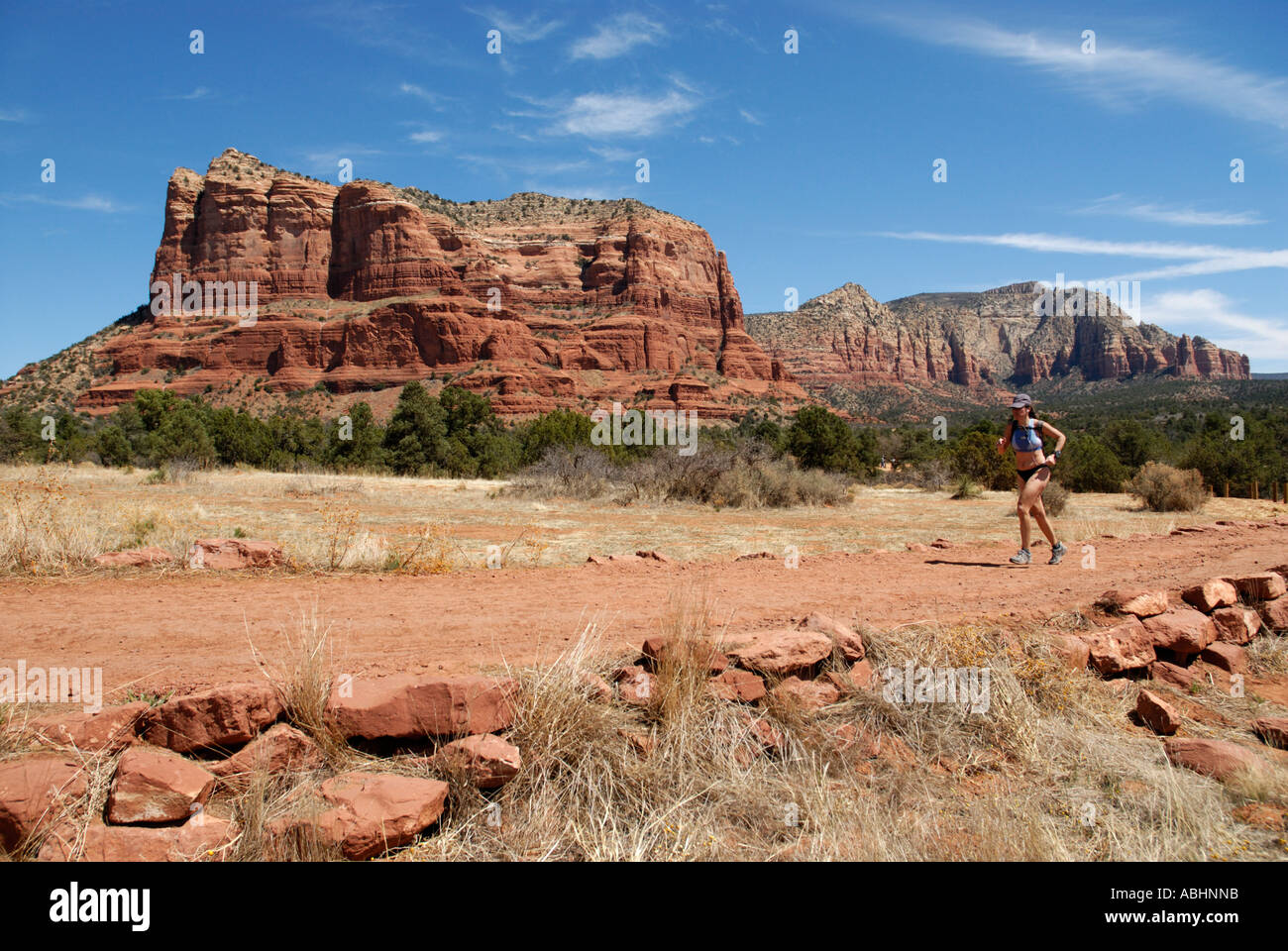 Donna atleta che corre la formazione su sentiero, Coconino National Forest, Courthouse Butte in background, vicino a Sedona, in Arizona Foto Stock