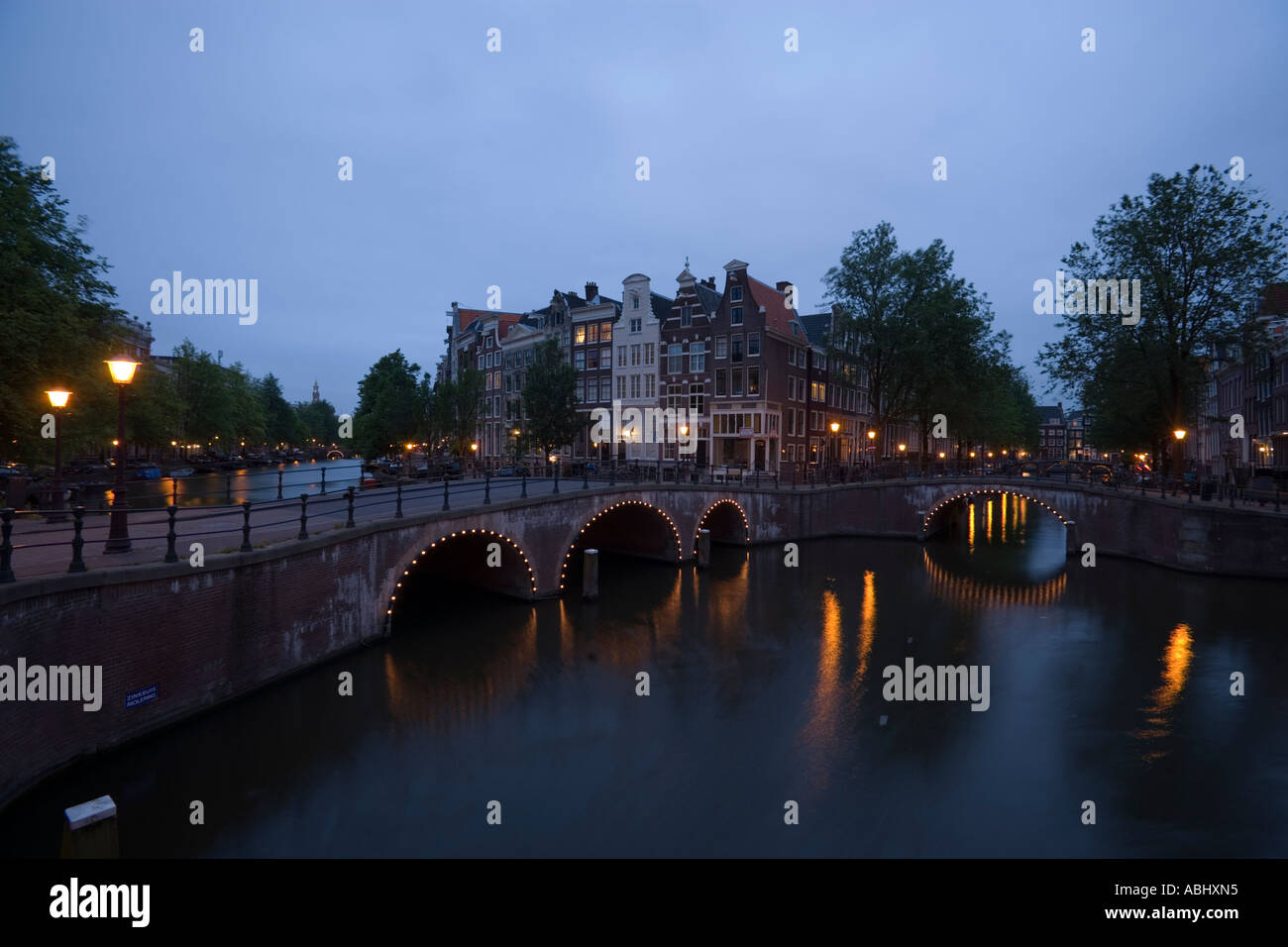 Vista su ponte illuminato di case a capanna in serata Keizersgracht e Leidsegracht Amsterdam Olanda Paesi Bassi Foto Stock