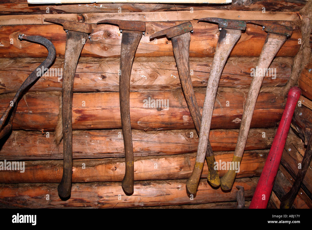 Visualizzazione di strumenti lumberjack appeso a una parete interna una fucina Foto Stock