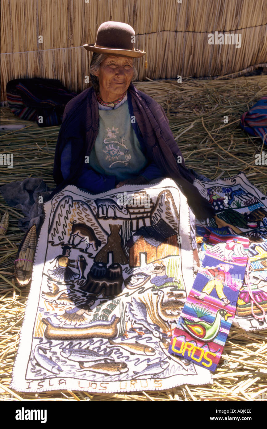 Il lago Titicaca, Perù. Vecchia donna mostra souvenir panno ricamato in un villaggio sull'isola galleggiante di Uros. Foto Stock