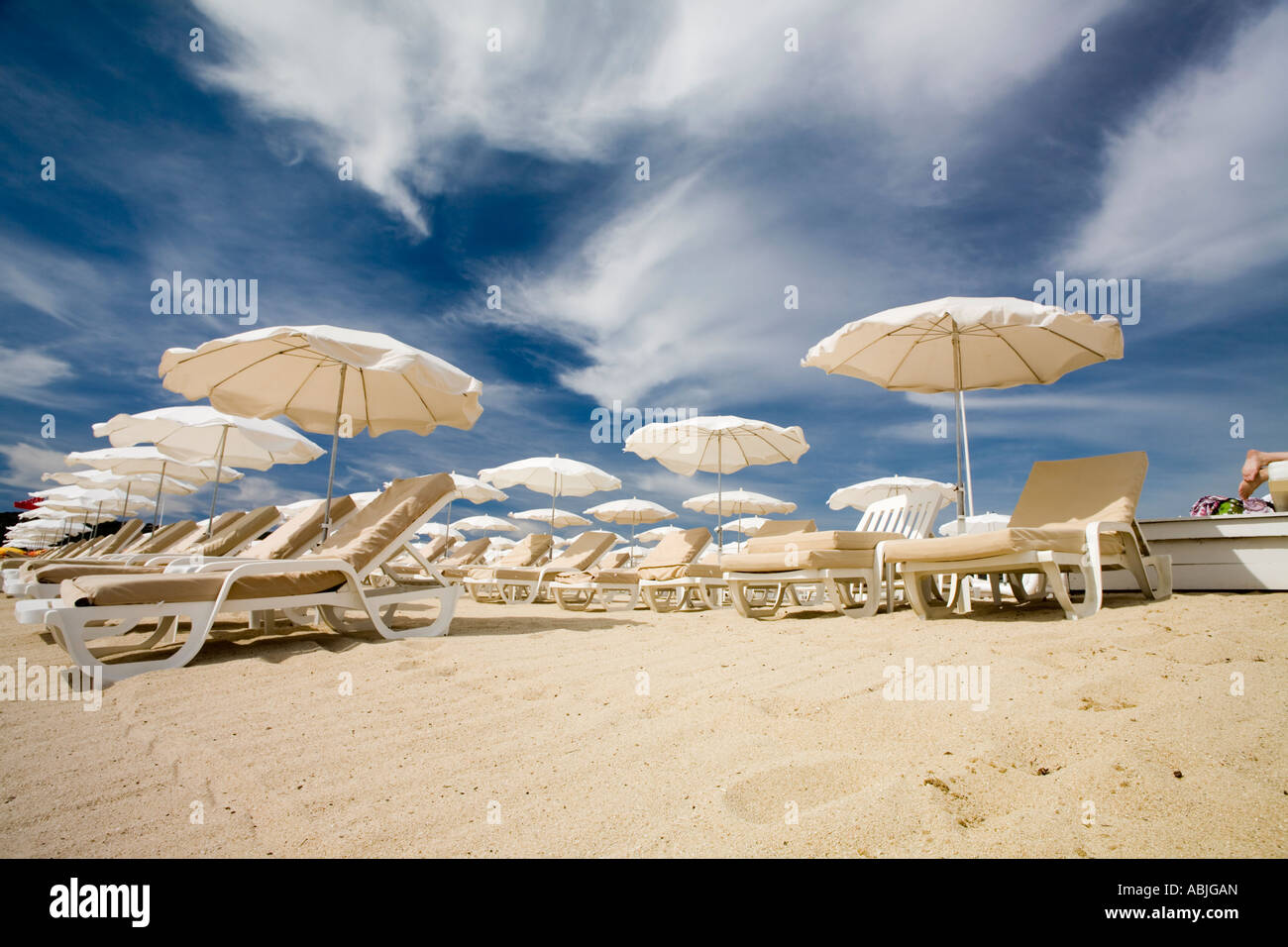 Ombrellone bianco colore crema e sedie lunghe sulla bellissima spiaggia di Pampelonne, Ramatuelle, Francia Foto Stock