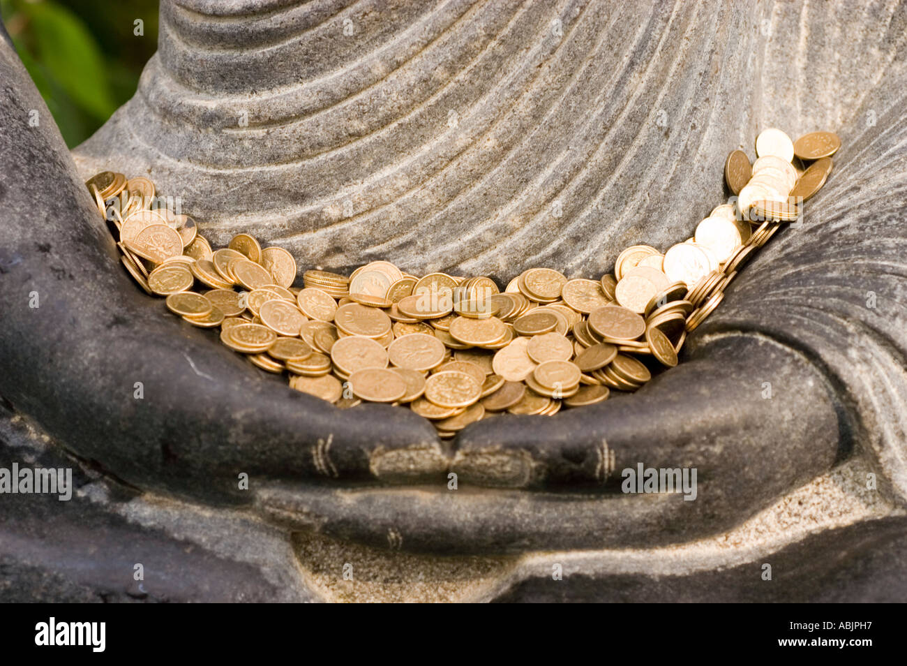 Monete d'oro nelle mani di una statua in pietra del Buddha che meditava a Bodhgaya sotto l'albero di Bodhi per raggiungere l'illuminazione. Foto Stock
