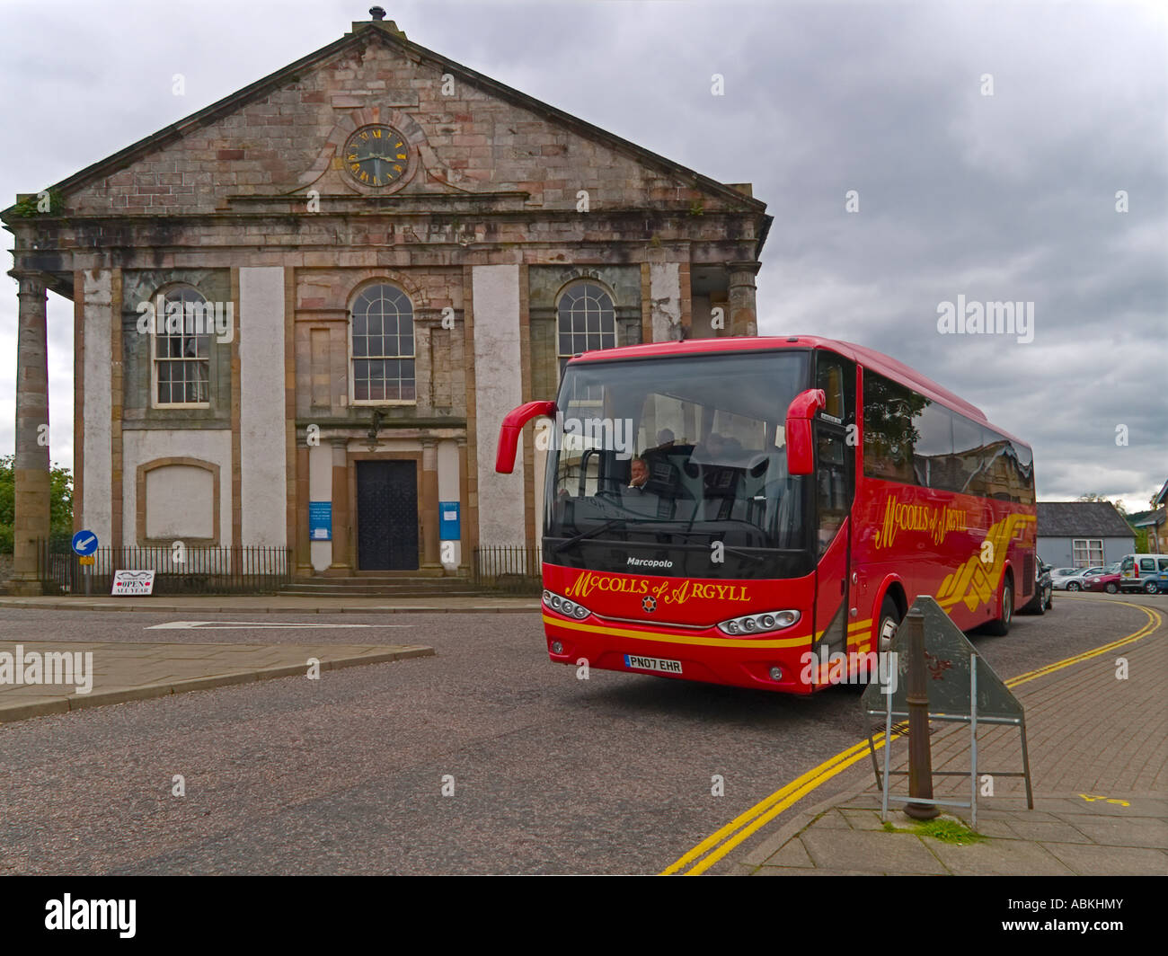 Un rosso brillante tour moderni bus fuori dalla chiesa parrocchiale di Inverary Scozia Scotland Foto Stock