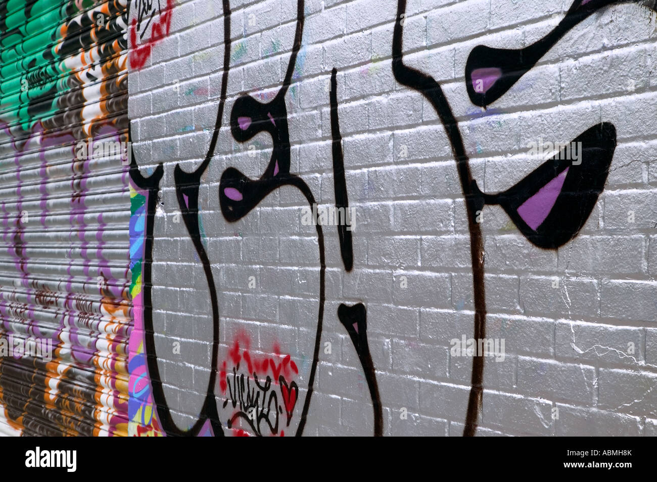 Graffiti su un muro di mattoni e serrande metalliche di un edificio abbandonato Foto Stock