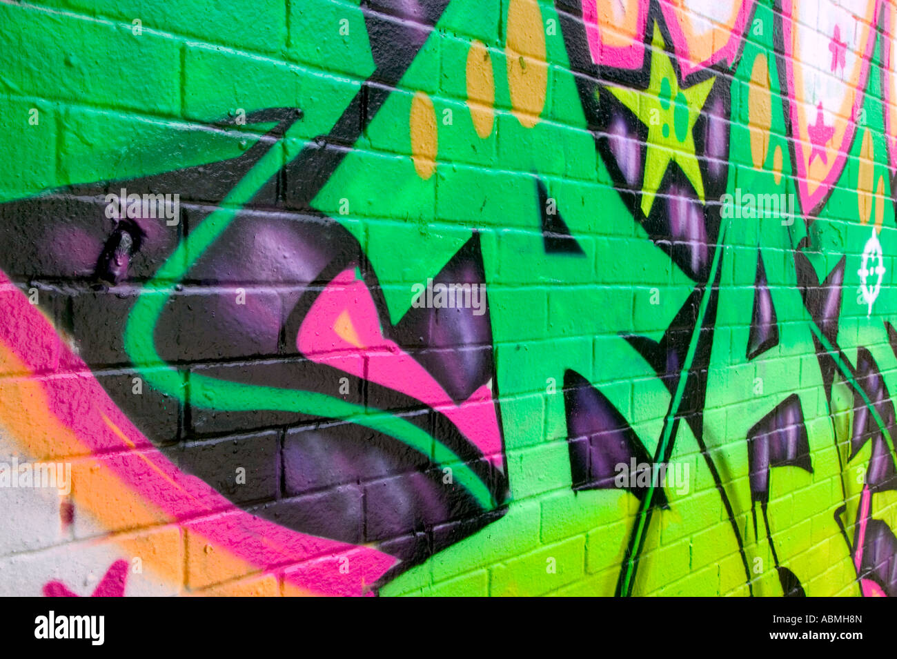 Graffiti con colori al neon spruzzata su un muro di mattoni di un edificio abbandonato Foto Stock