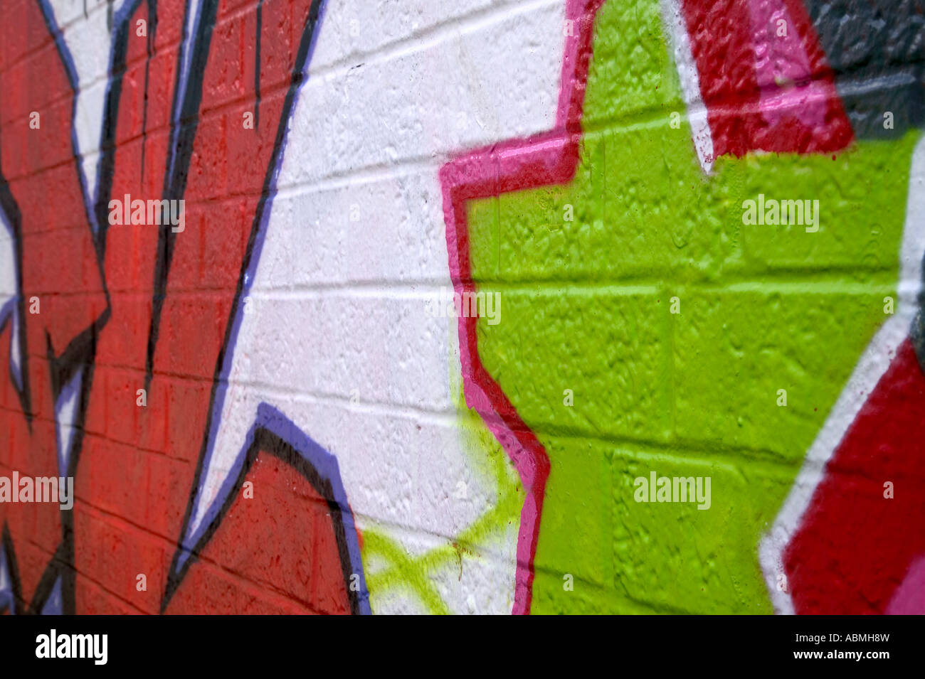 Graffiti spruzzato su un muro di mattoni in prospettiva laterale Foto Stock