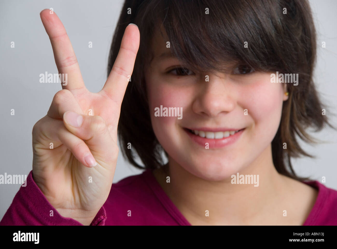 La giovane ragazza di 11 anni che dà il segno V per la vittoria chiamato anche segno di pace Foto Stock