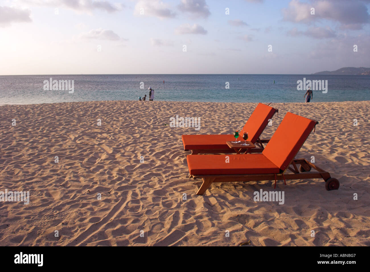 Due caratteri vuoti con bevande sulla spiaggia di sabbia dorata nel tardo pomeriggio Grand Anse Beach Grenada Caraibi Foto Stock