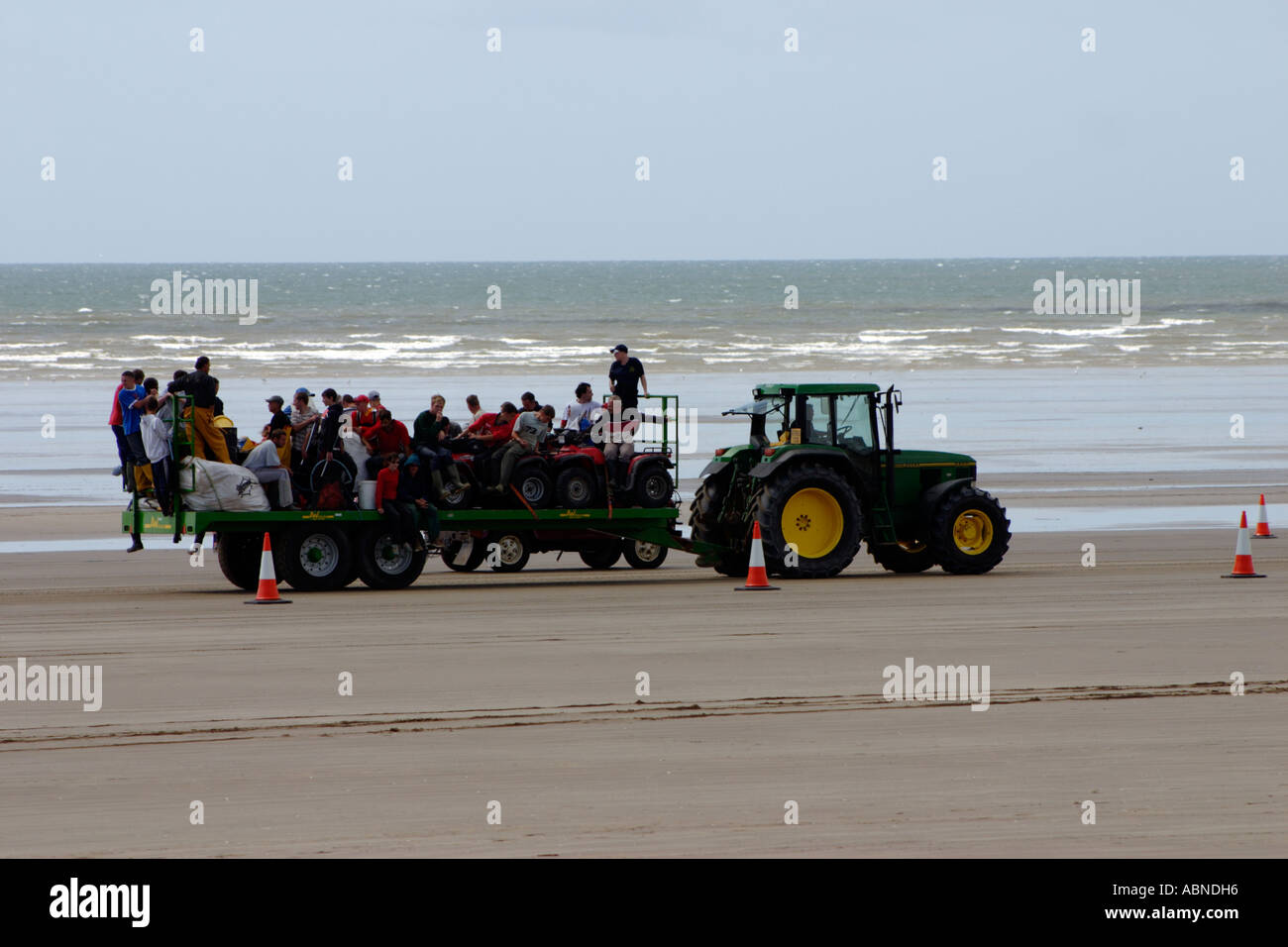 Il trattore sulla spiaggia con rimorchio di arricciatura raccoglitori Foto Stock