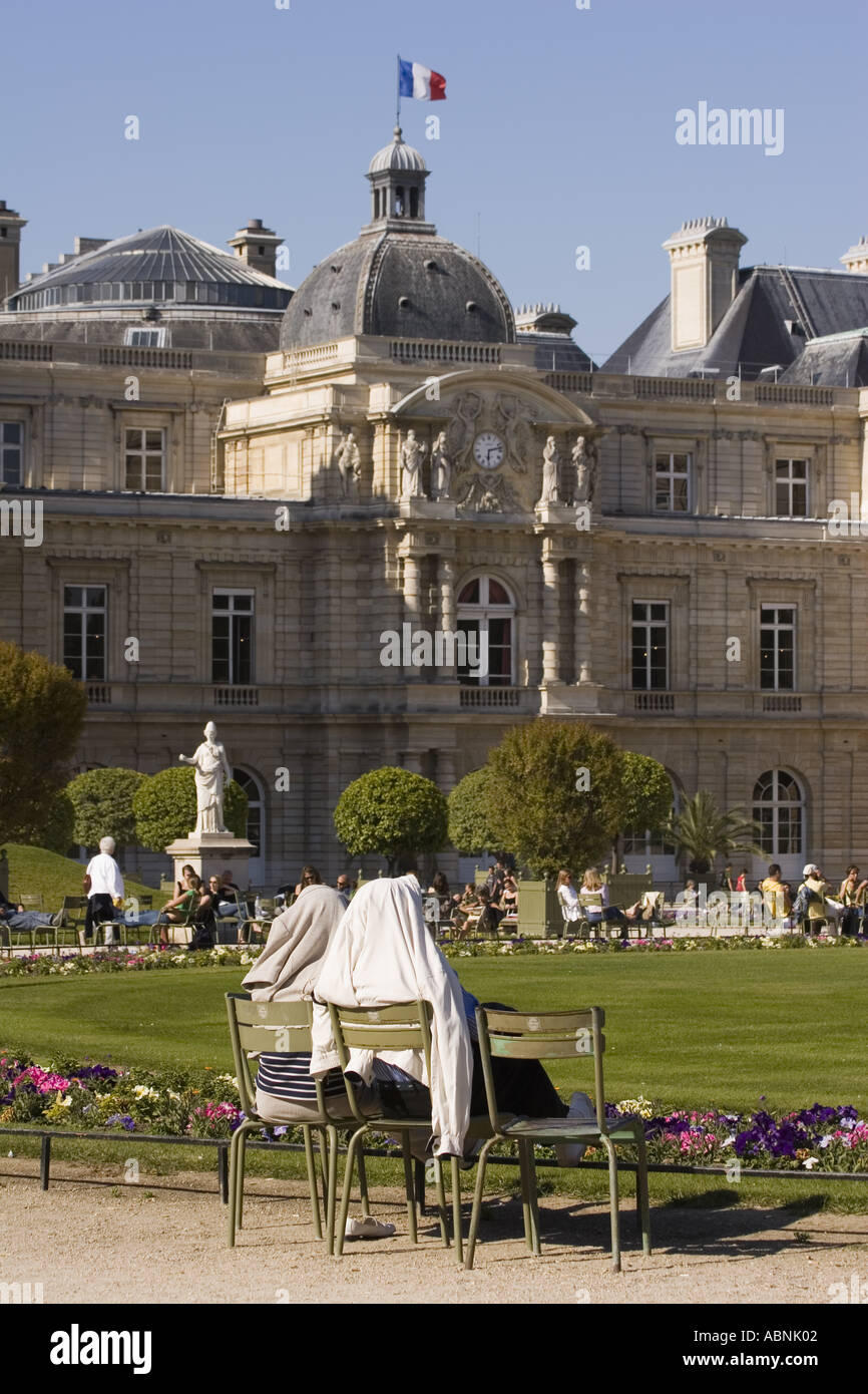 Due persone sedersi con i cappotti sopra le loro teste per tenere al caldo sole spento al Jardin du Luxembourg Parigi Francia Foto Stock